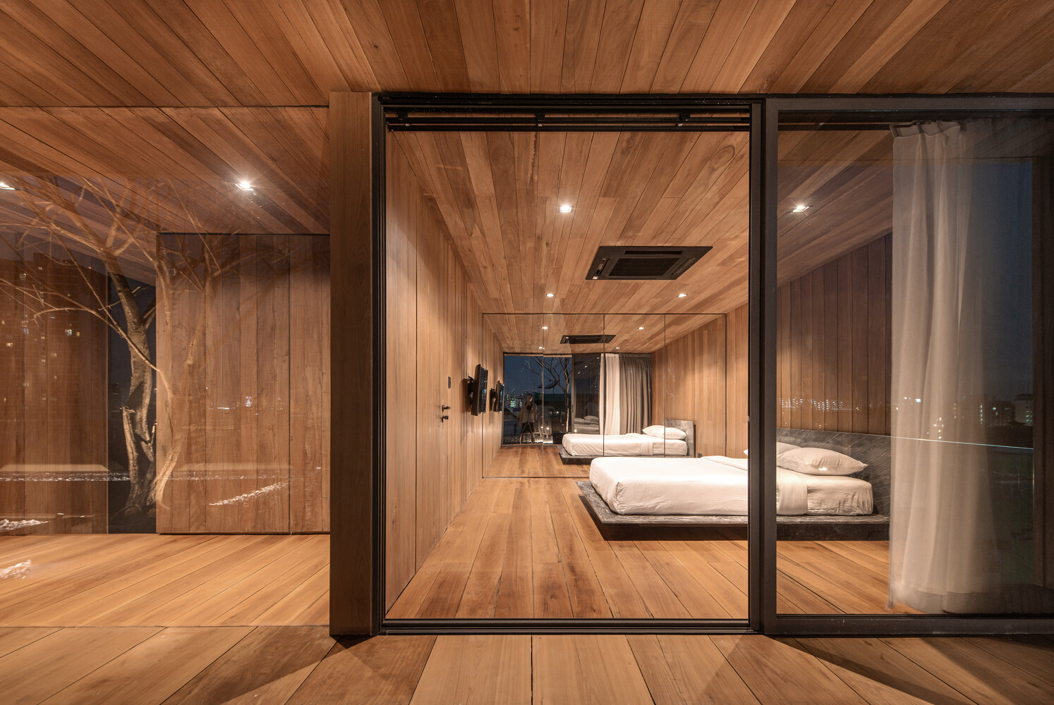 Sliding glass doors connect the bedroom to an outdoor rooftop space finished with pebbles.