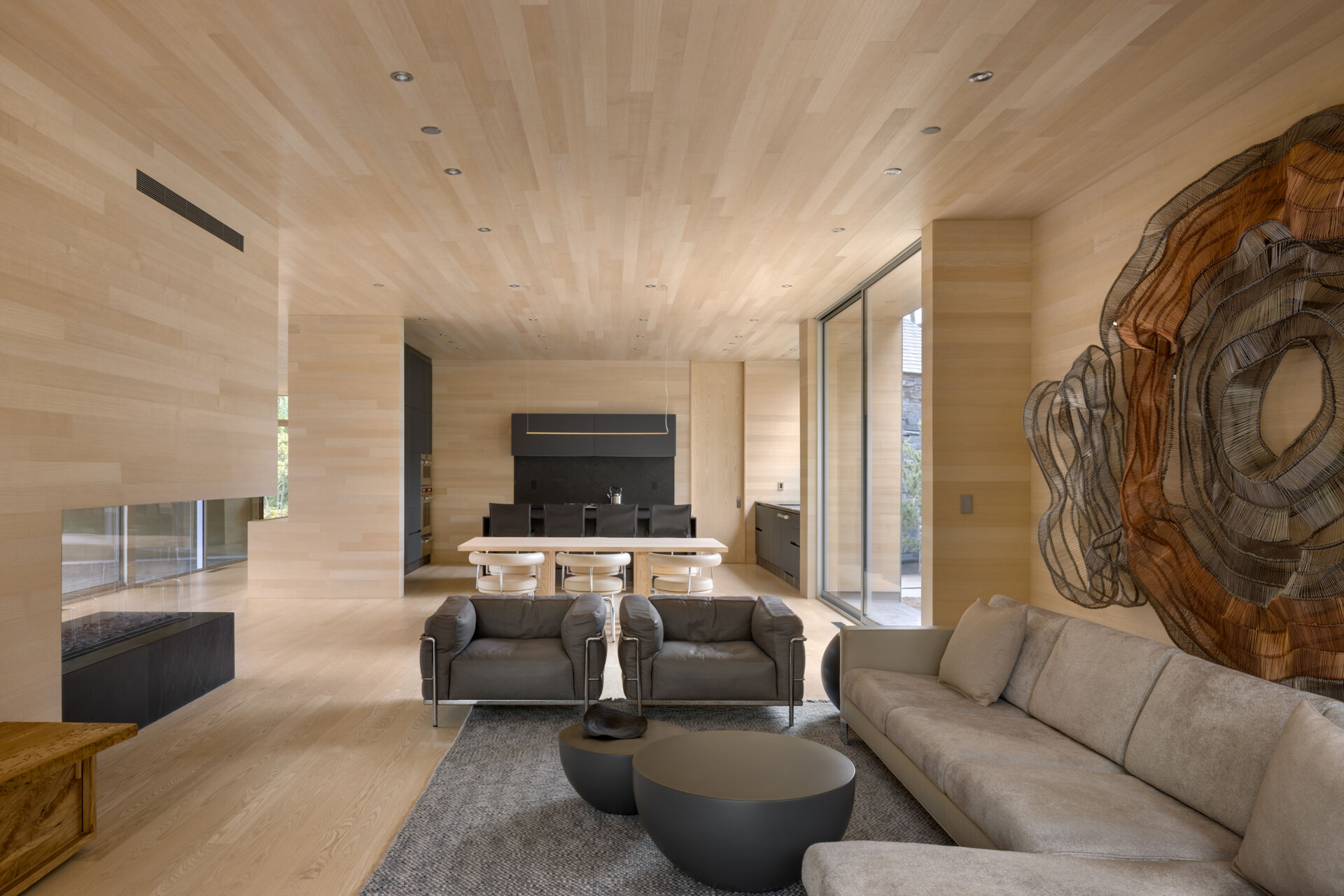 El salón de madera está enmarcado por una amplia pared de cristal que va del suelo al techo. Estas aberturas permiten vistas ininterrumpidas de la espectacular topografía del sitio. Los espacios interiores permanecen tranquilos y sobrios, permitiendo que la vista tenga prioridad visual durante todo el día.