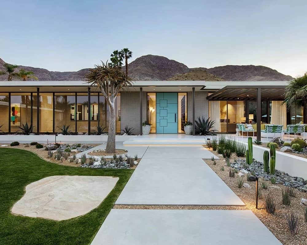 A mid century modern exterior in Rancho Mirage featuring brick, stucco, painted steel, and concrete walkways set against the desert landscape.