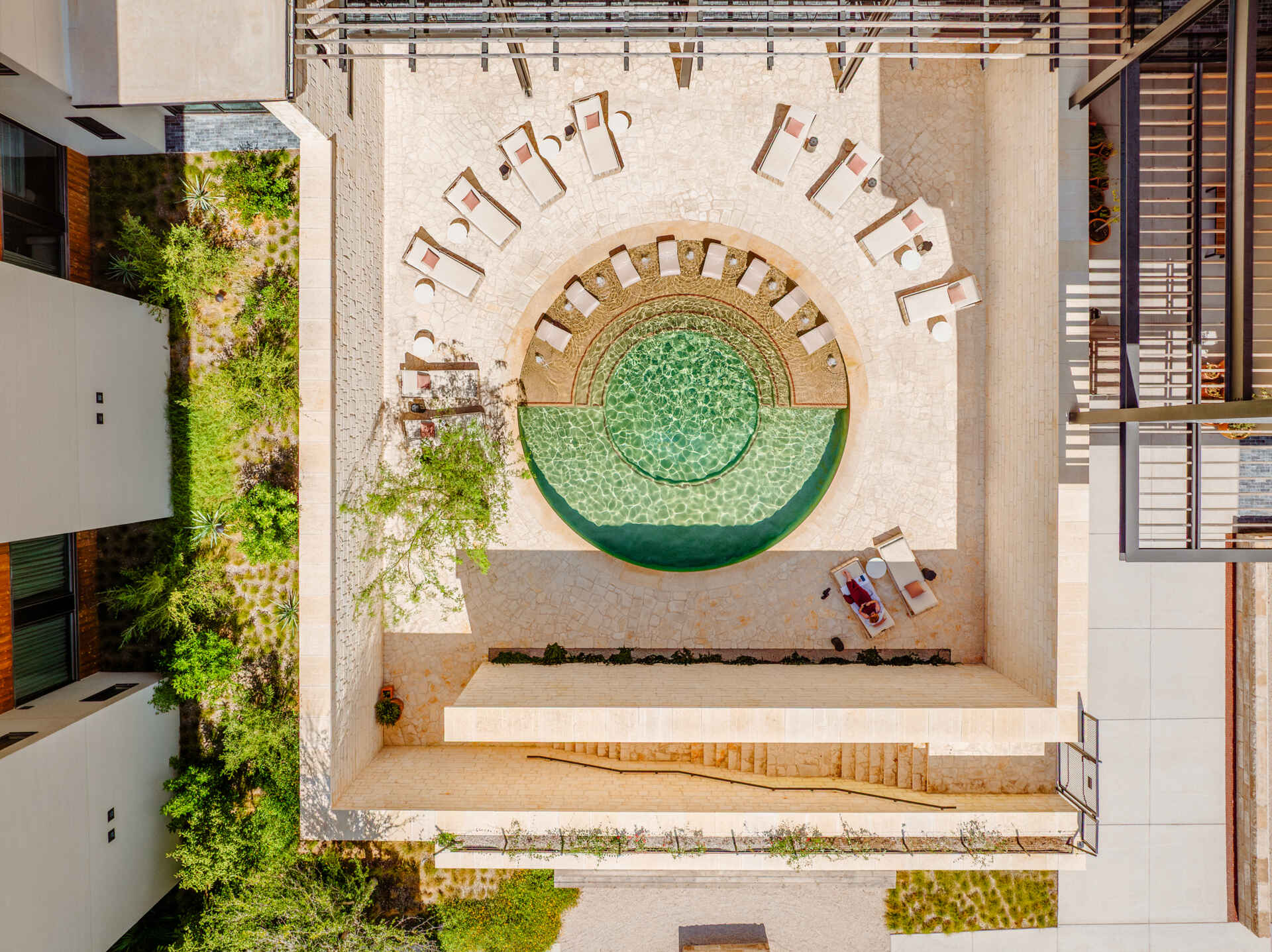 A sunken outdoor limestone pool anchors the outdoor amenities. Paired with a lounge area, it offers a sheltered place to step away from the heat while remaining within the landscape of the property.