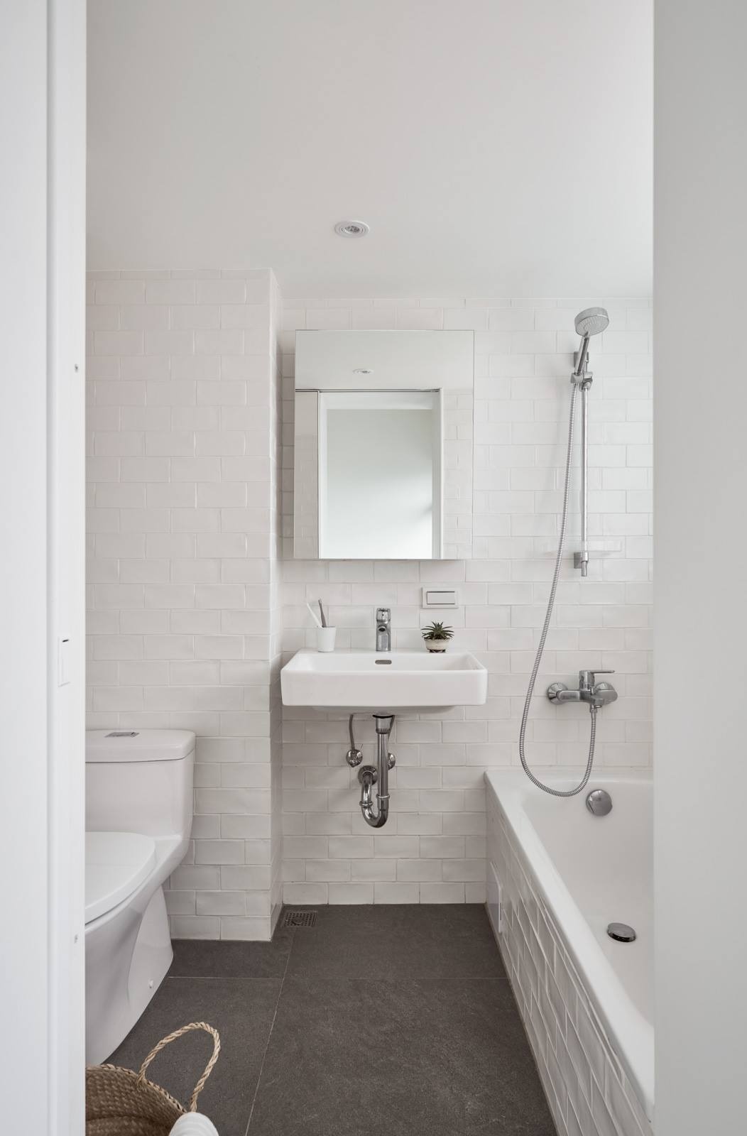 White walls and smart layout choices make this small Taipei bathroom feel bright and functional, complete with open shelving and a bath shower combo.