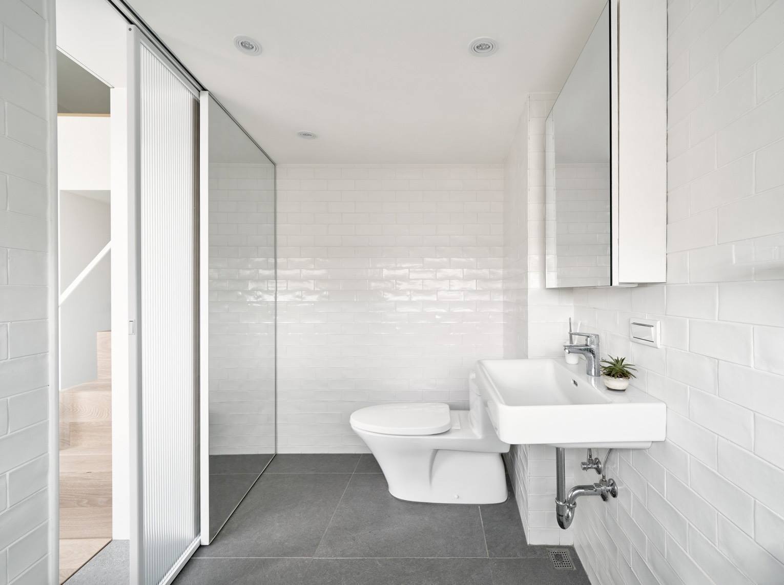 White walls and smart layout choices make this small Taipei bathroom feel bright and functional, complete with open shelving and a bath shower combo.