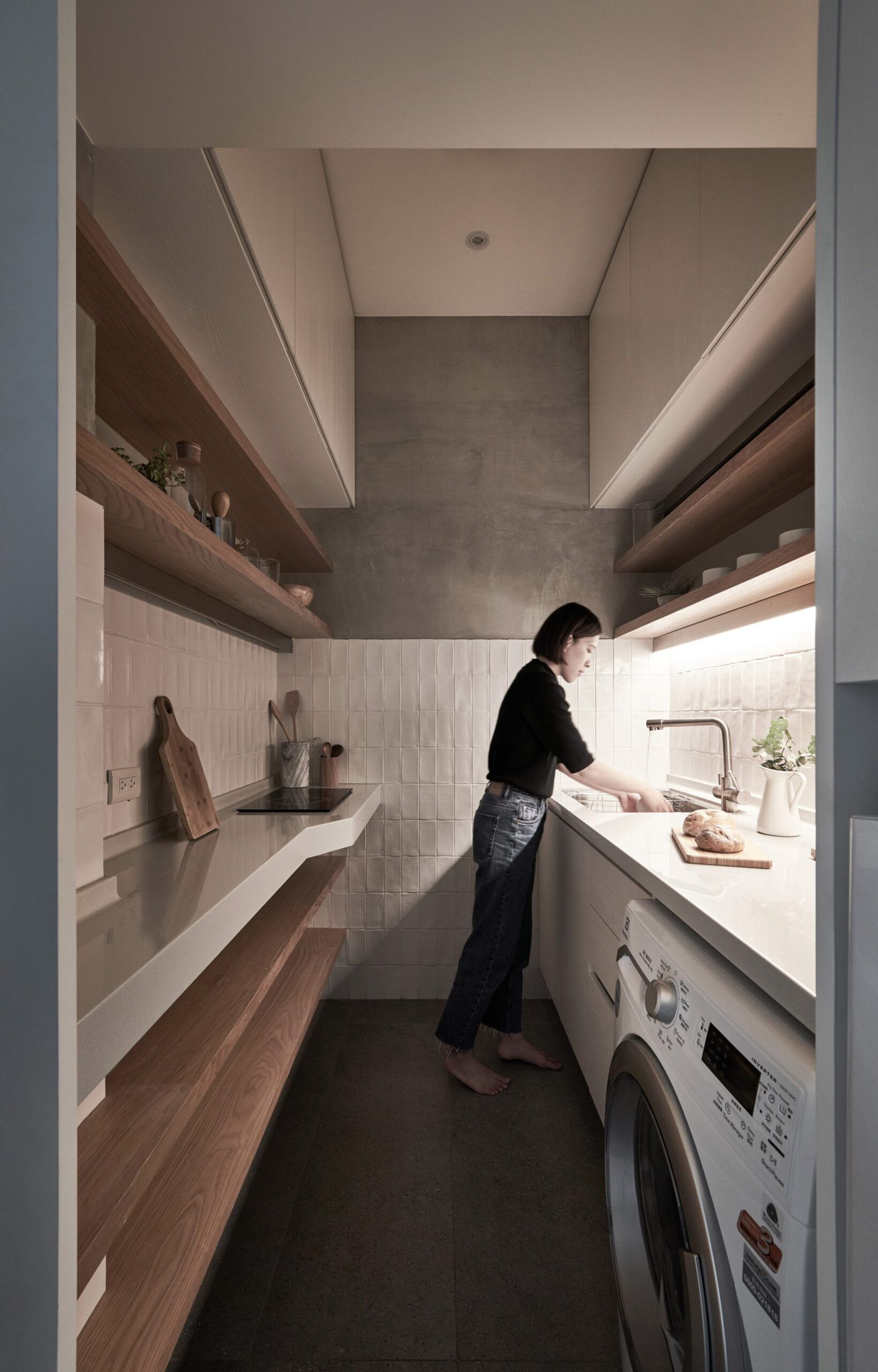 This tiny Taipei kitchen fits a fridge, washer dryer and stove into a streamlined layout that balances warm wood shelving with practical storage.