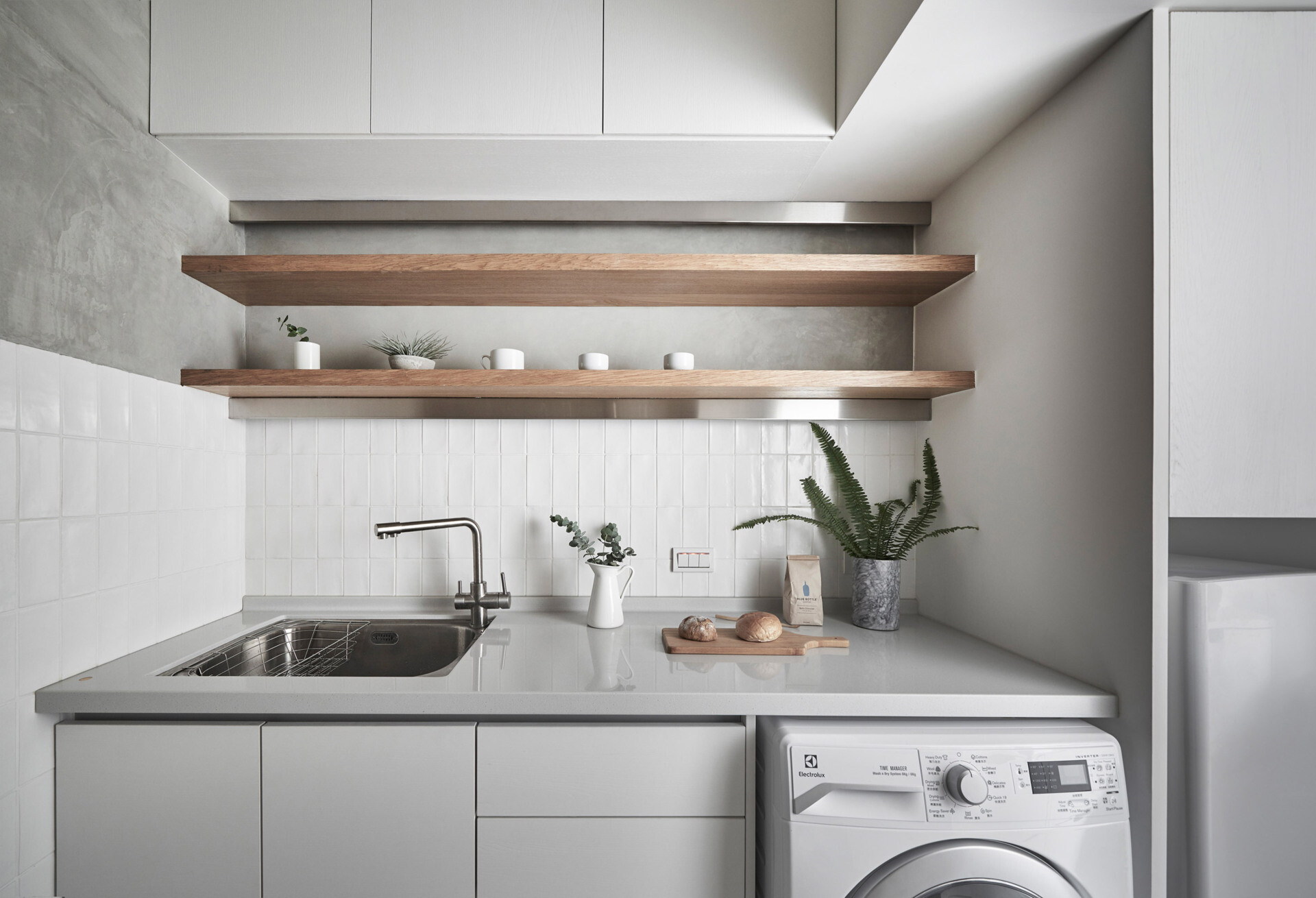 This tiny Taipei kitchen fits a fridge, washer dryer and stove into a streamlined layout that balances warm wood shelving with practical storage.