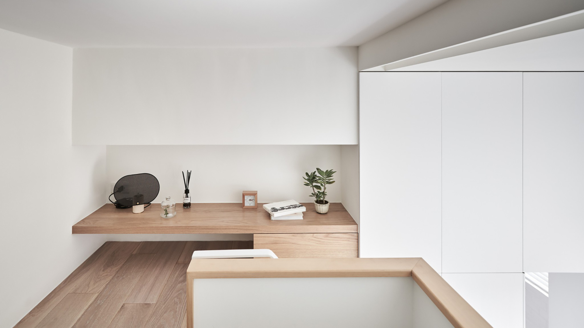 A minimalist loft bedroom crowns this tiny Taipei apartment, featuring built in shelving and a clean headboard wall for a calm sleeping zone.
