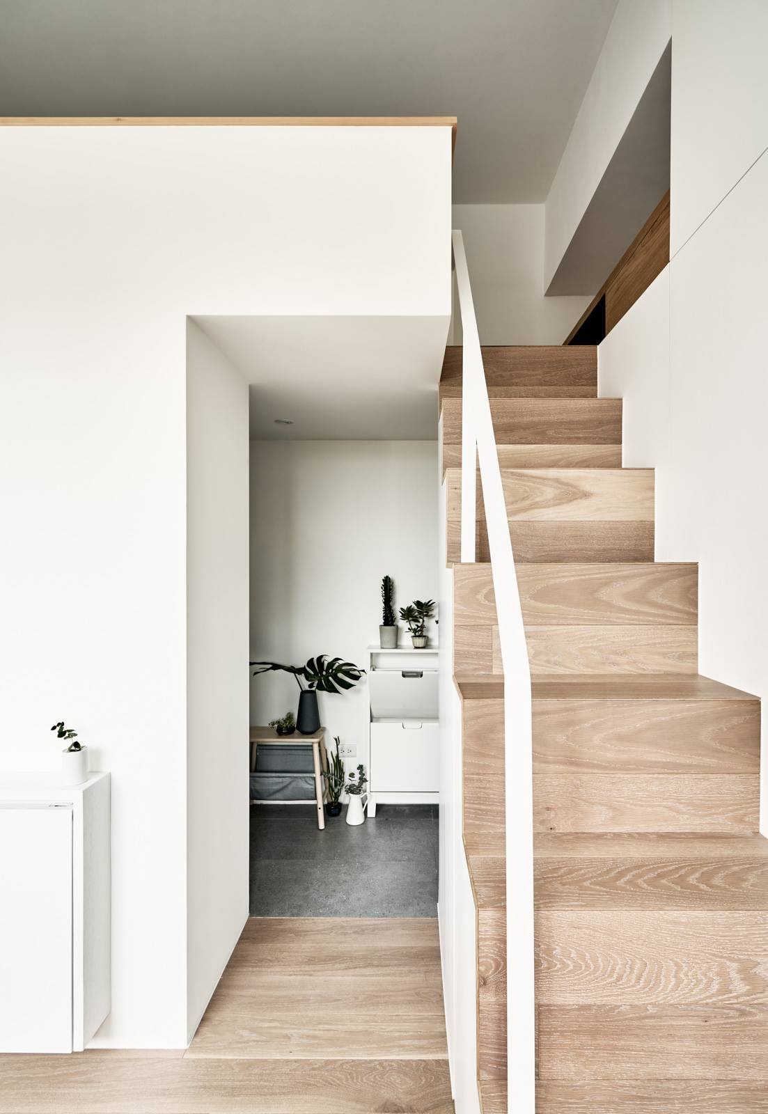 Wood stairs in this Taipei micro flat hide built in storage and appliances, proving every element can serve more than one purpose.