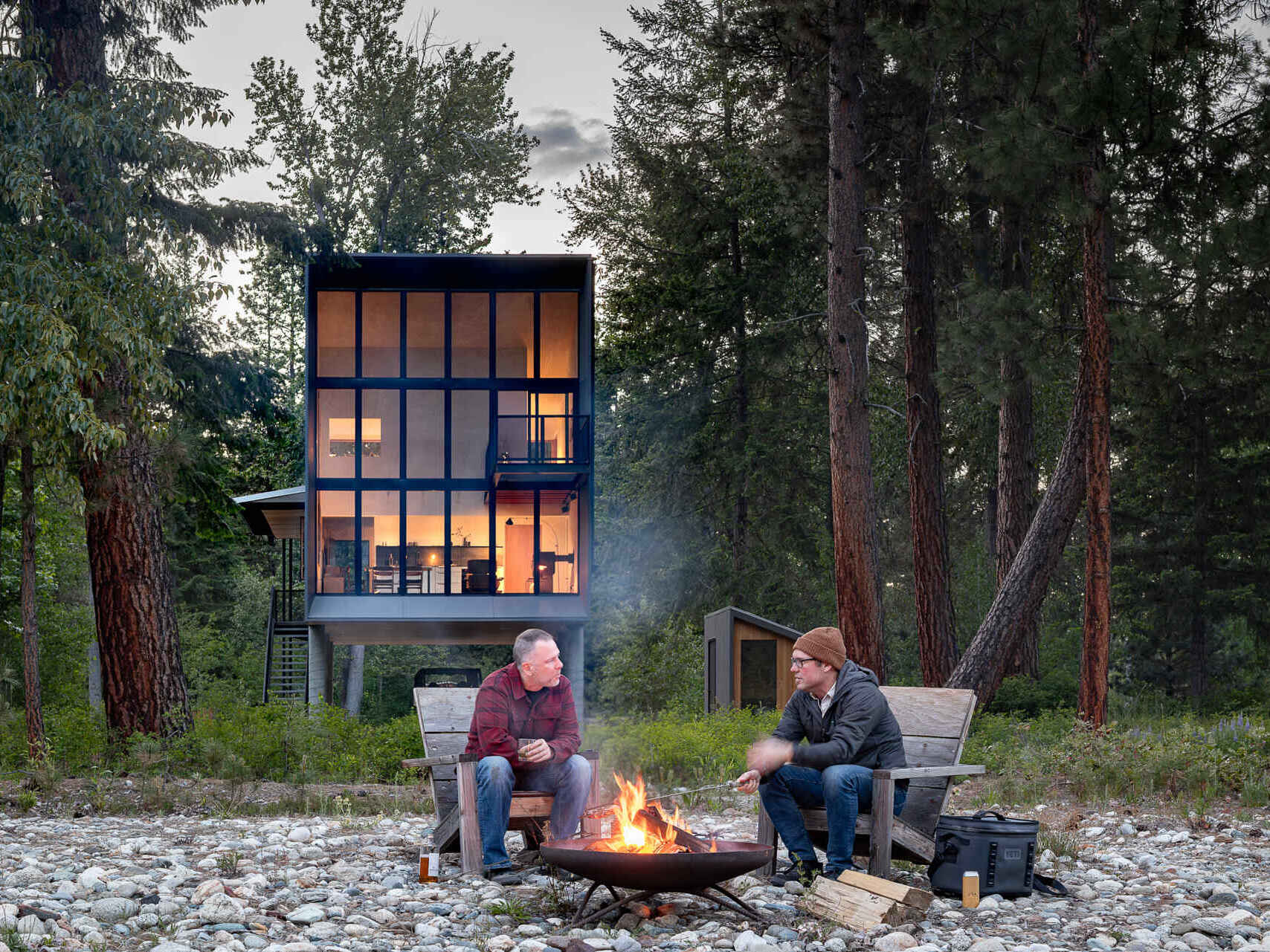 An elevated cabin in Plain, Washington rises above the Wenatchee River floodplain, using cedar, steel, and concrete to live lightly within the forest.