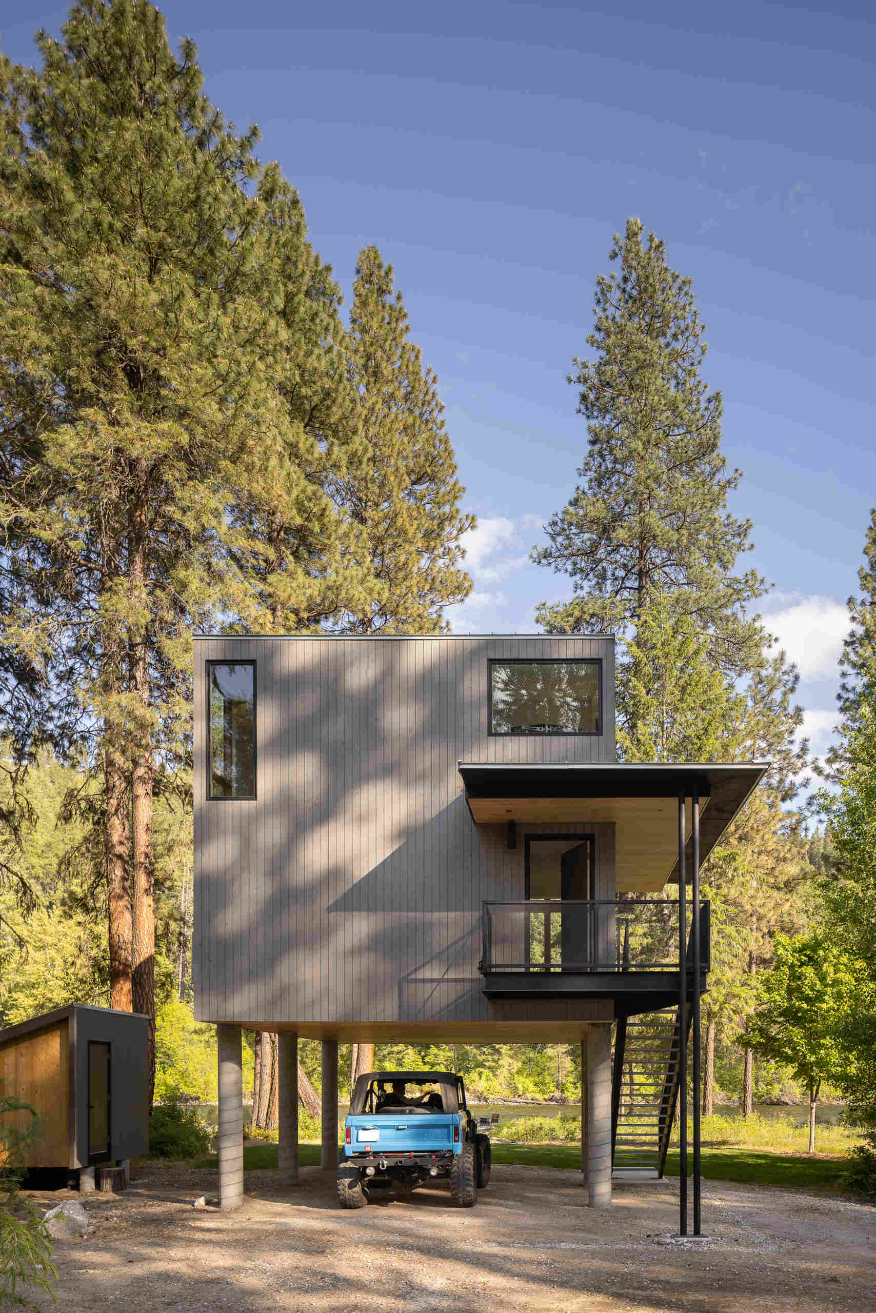 An elevated cabin in Plain, Washington rises above the Wenatchee River floodplain, using cedar, steel, and concrete to live lightly within the forest.