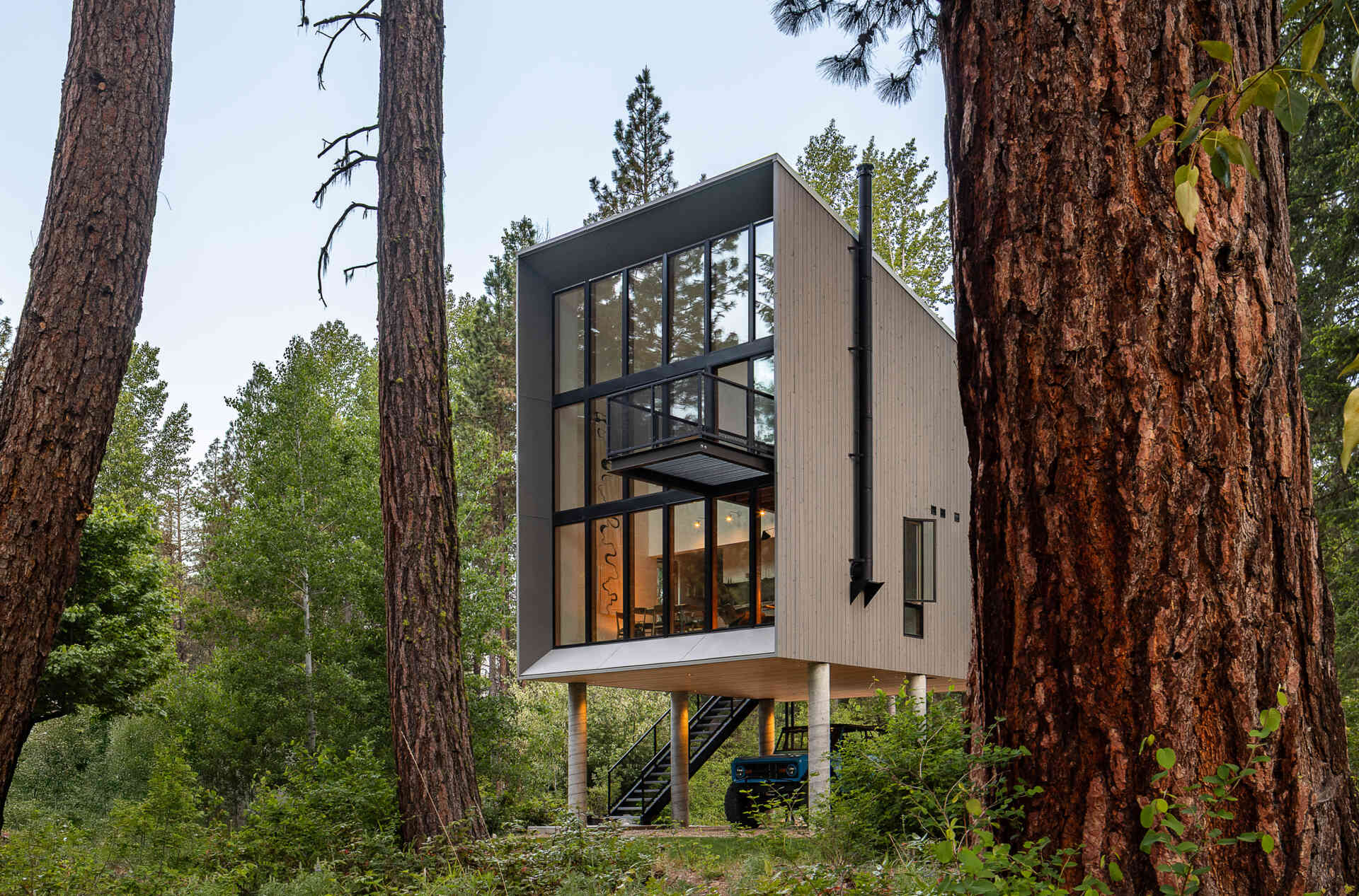 A twenty-foot-wide window wall frames river views while maintaining privacy, becoming the defining feature of this compact cabin.