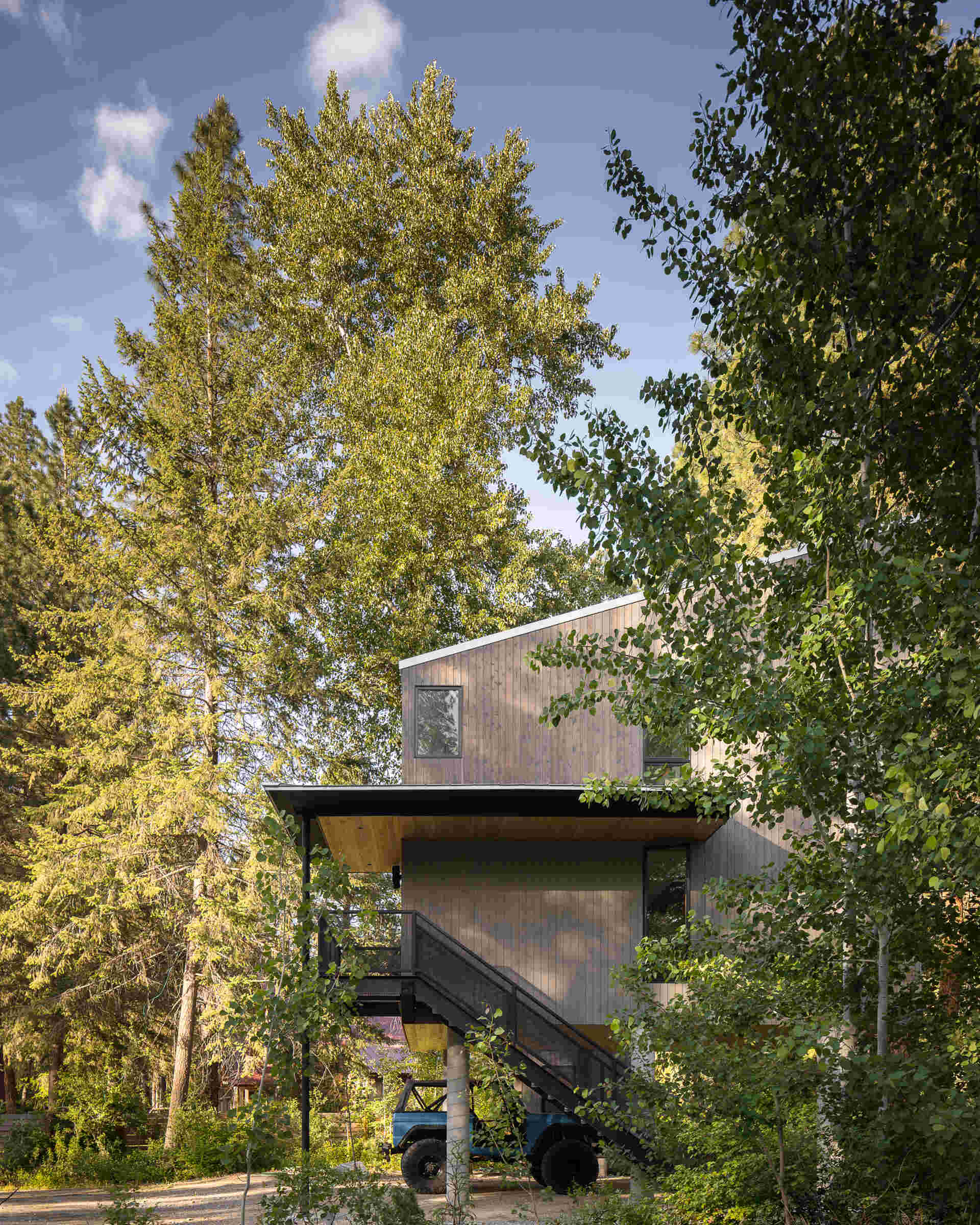 An elevated cabin in Plain, Washington rises above the Wenatchee River floodplain, using cedar, steel, and concrete to live lightly within the forest.