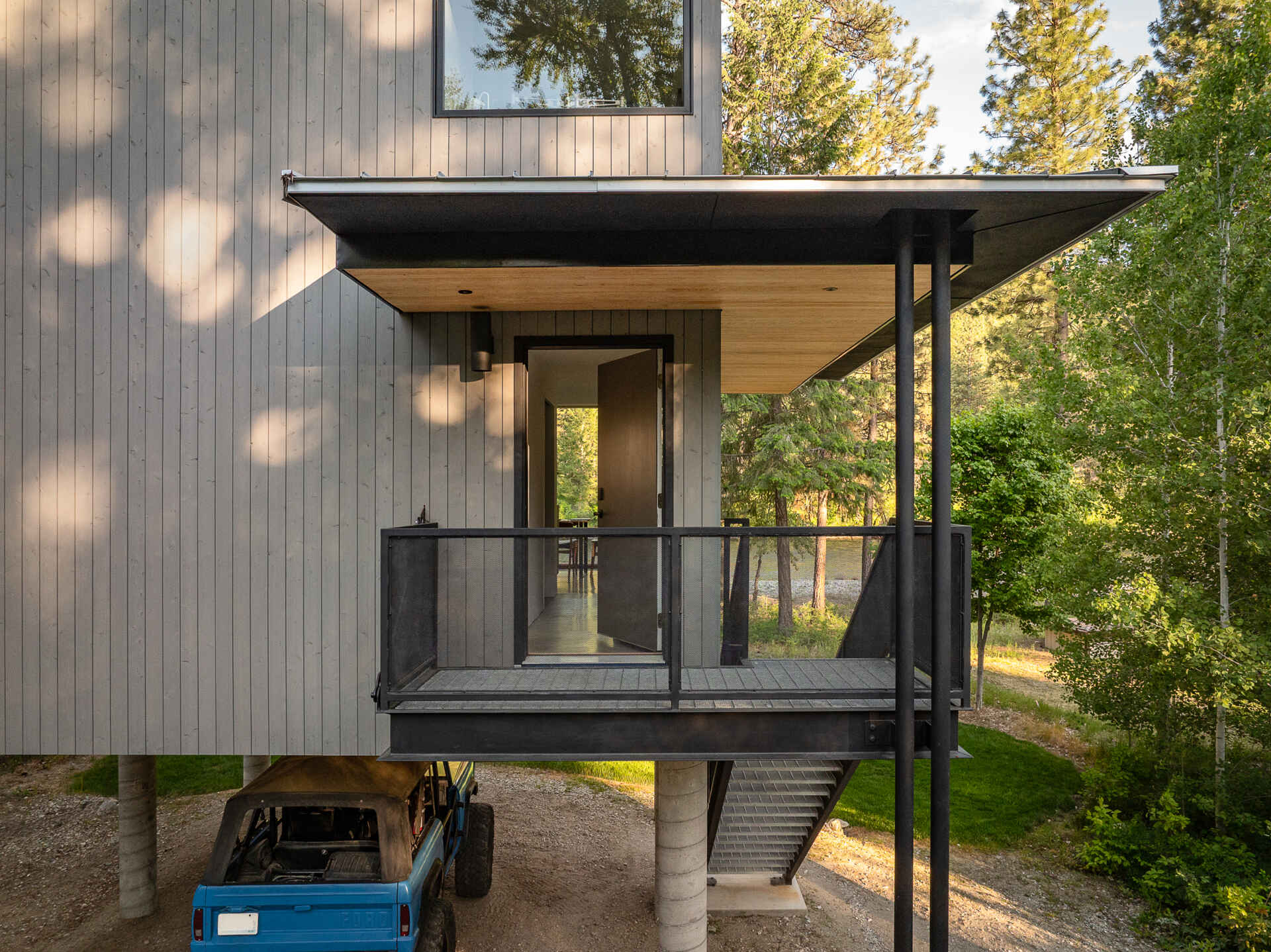 An elevated cabin in Plain, Washington rises above the Wenatchee River floodplain, using cedar, steel, and concrete to live lightly within the forest.