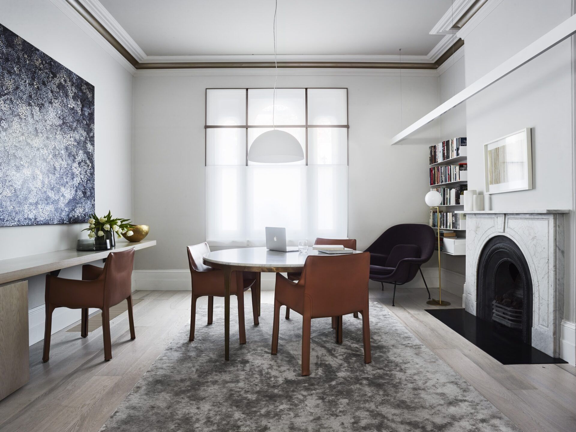 Una oficina en casa llena de luz diseñada para exhibir arte en un interior neutro.