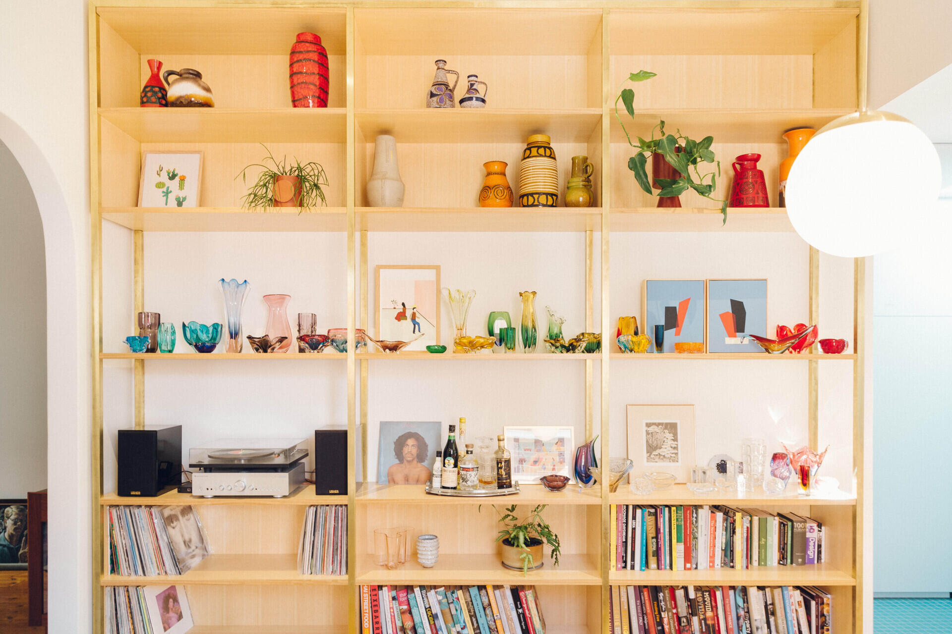 Timber shelving showcases Italian and Czech glassware alongside German pottery and books.