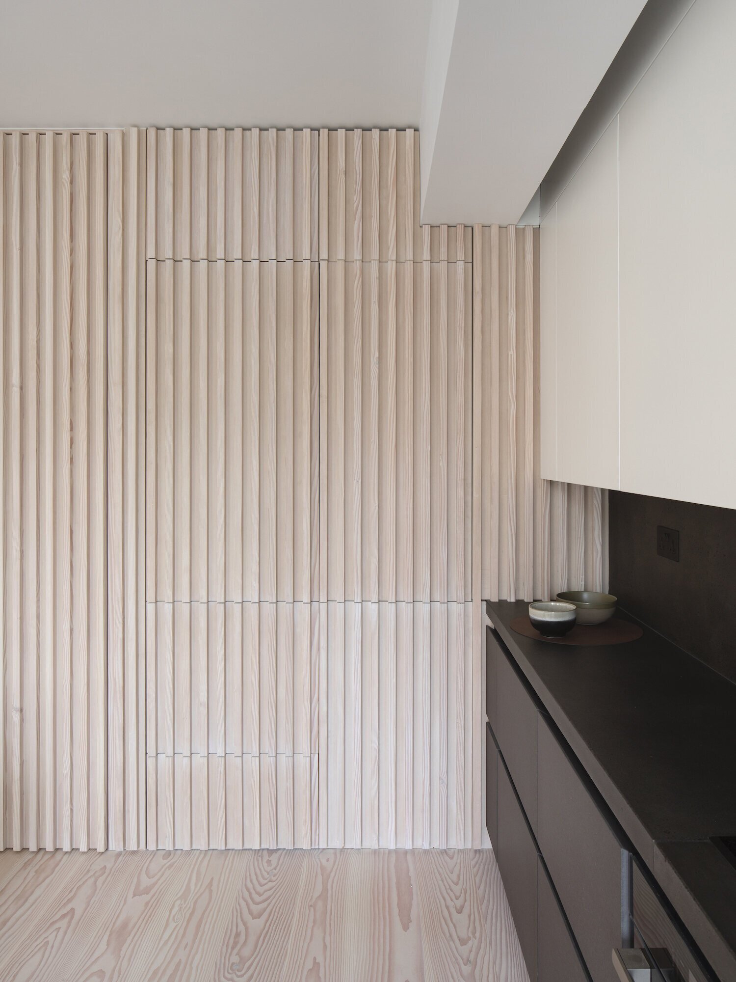 All kitchen appliances and hanging cupboards are cleverly incorporated into the timber wall, keeping the apartment efficient and uncluttered.