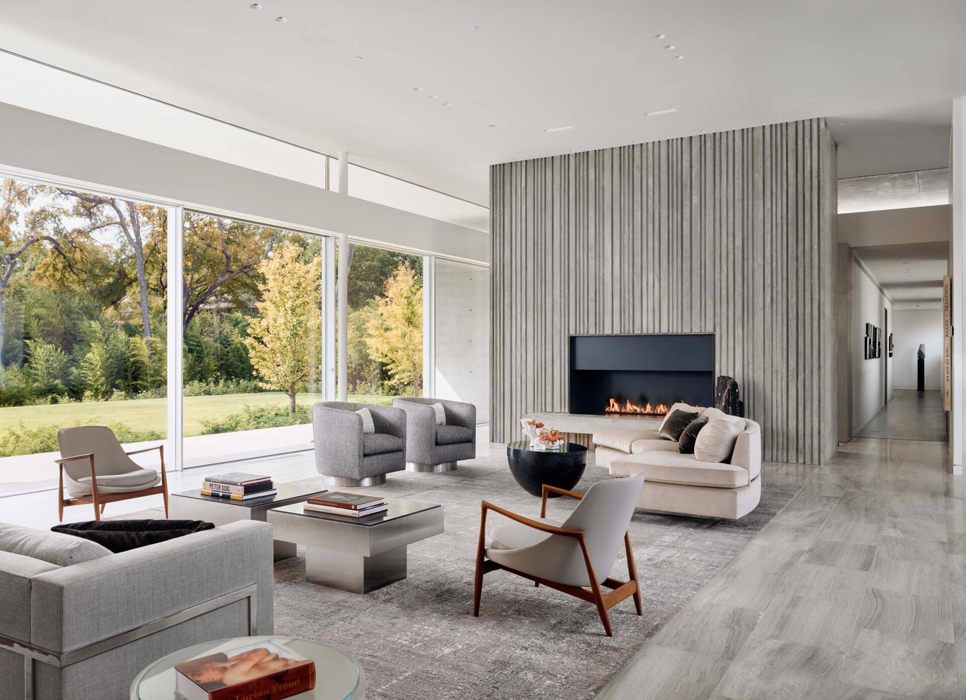 Inside the living room, a corrugated concrete fireplace surround adds vertical texture and height, echoing the exterior walls and unifying the design.