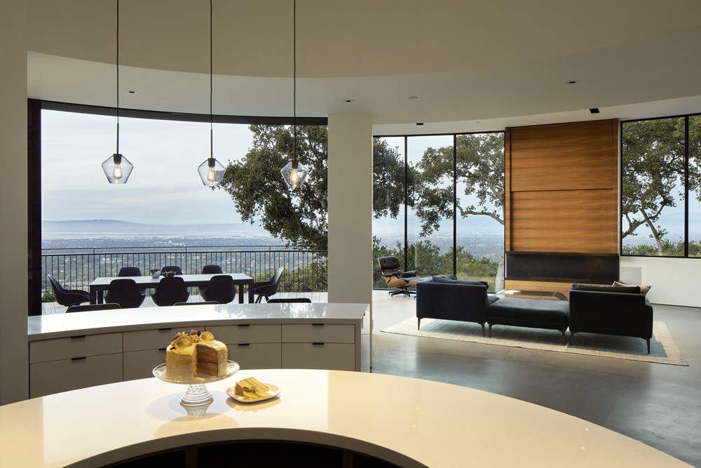 Curved pocket doors disappear into the walls, allowing the living room to flow directly onto the deck and frame sweeping South Bay views.