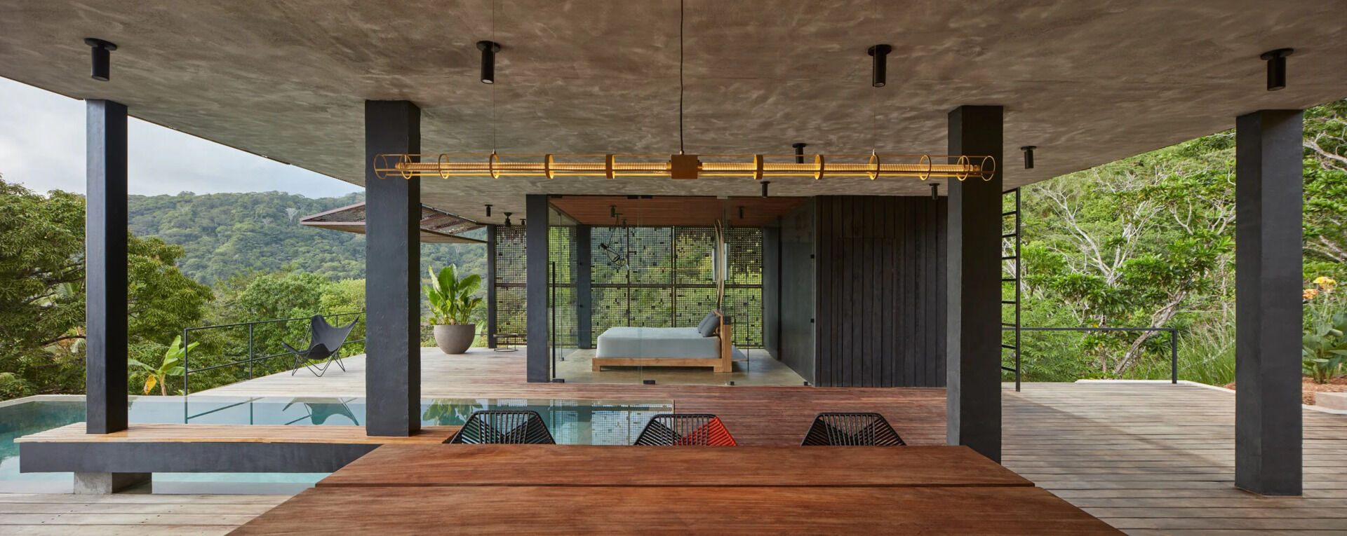 At one end of the house, a glass enclosed primary bedroom opens directly to panoramic jungle views.
