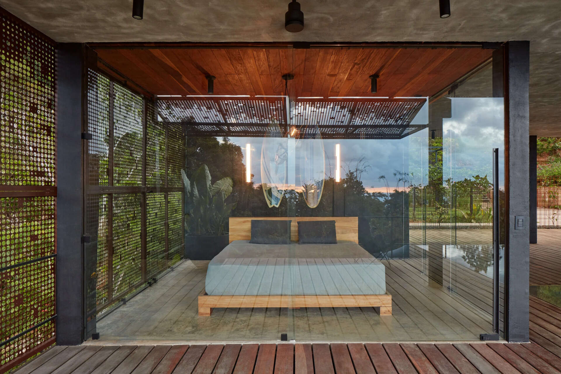 At one end of the house, a glass enclosed primary bedroom opens directly to panoramic jungle views.