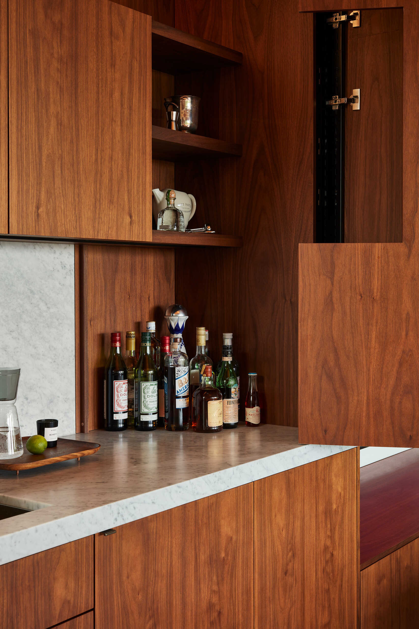 Los gabinetes personalizados continúan con el tema de la funcionalidad oculta. Un mueble bar con puertas plegables puede transformar el espacio durante las reuniones navideñas.