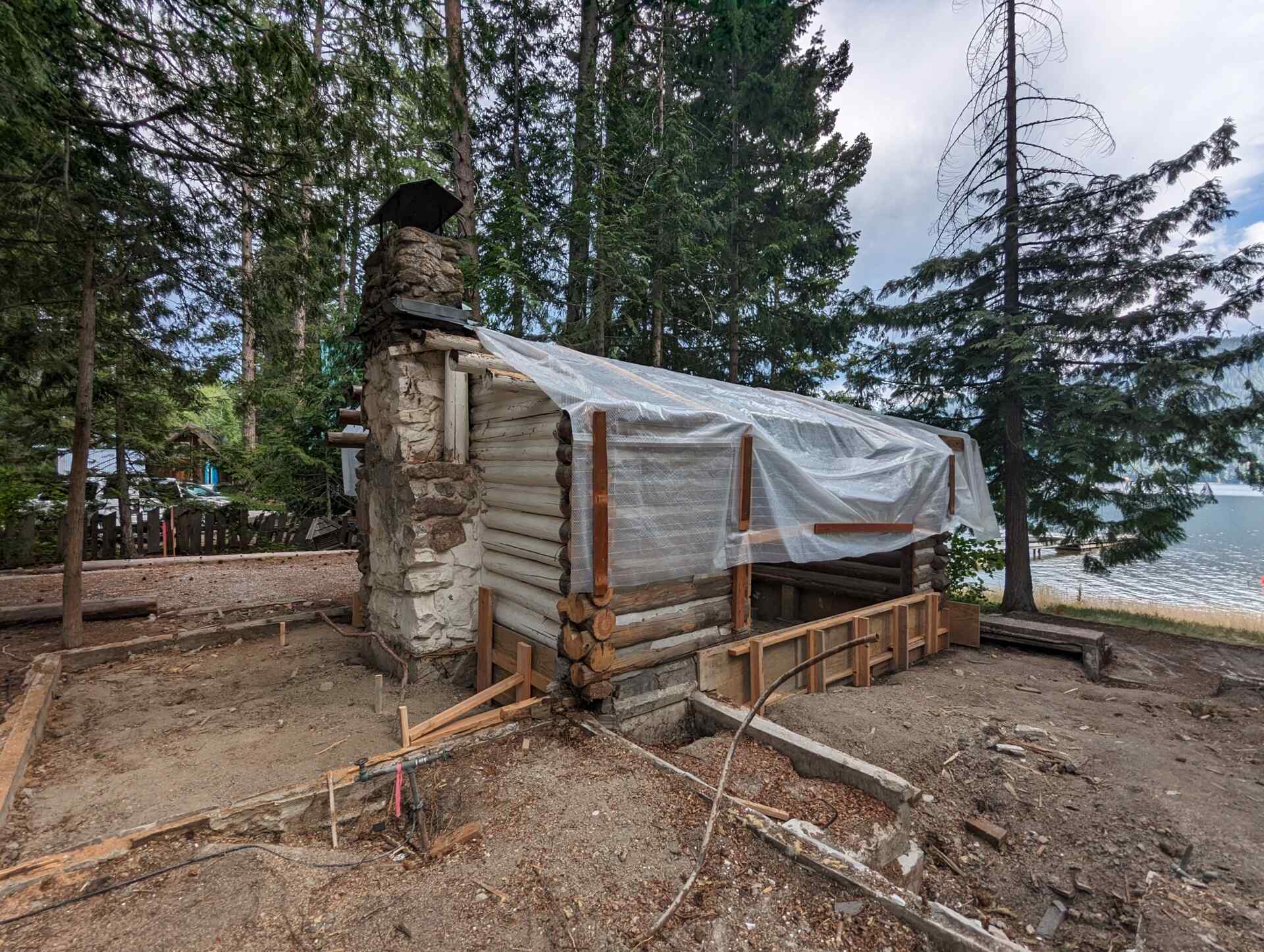 The original one-room log cabin from 1915 remains intact, revealing hand-hewn logs and a stone chimney beneath later additions. 