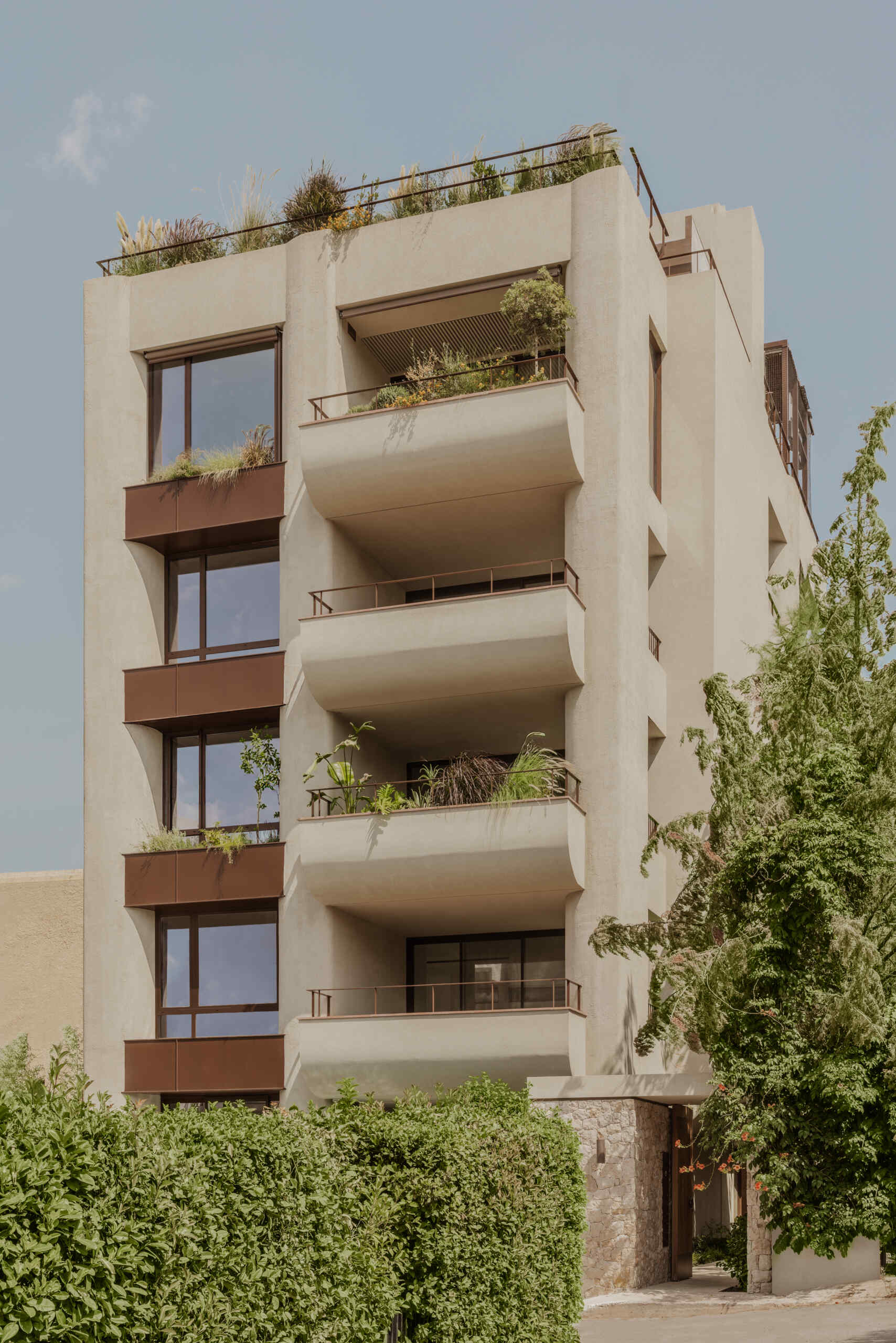 A geometric yet softly sculpted apartment building in Papagou, Athens, blending International Style references with curves, timber detailing and Mediterranean planting by Block722.