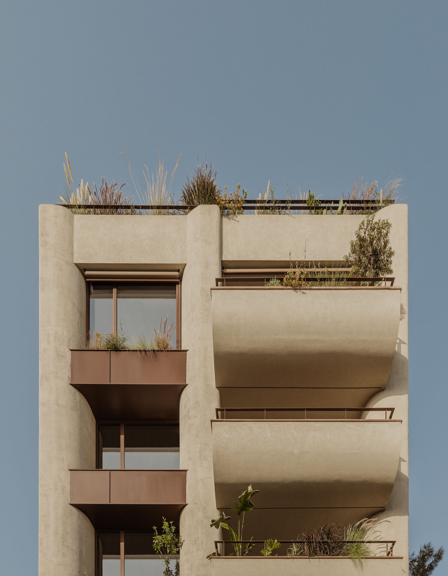 A geometric yet softly sculpted apartment building in Papagou, Athens, blending International Style references with curves, timber detailing and Mediterranean planting by Block722.