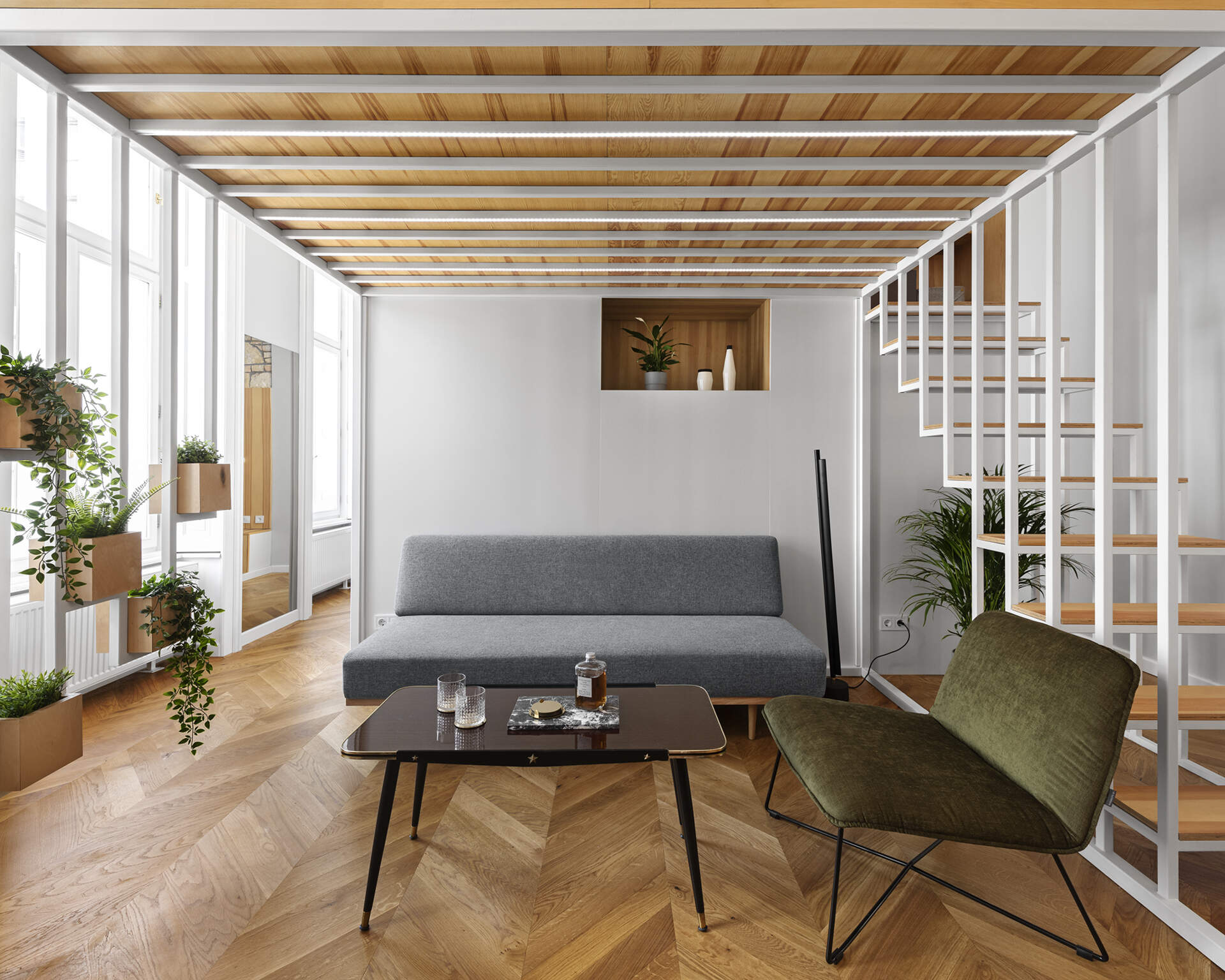 A calm living space with built in wood storage, indoor plants, and doors opening to a small balcony in the heart of Budapest.
