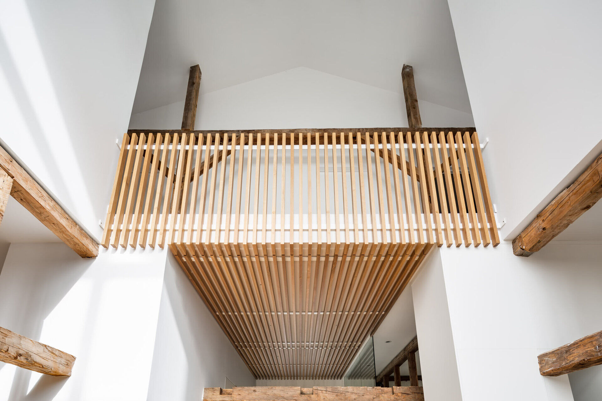 An upper level balcony overlooks the dining area, emphasizing the barn’s height and open layout.