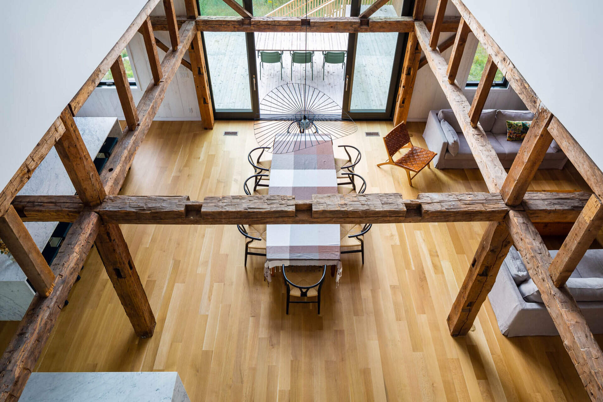 An upper level balcony overlooks the dining area, emphasizing the barn’s height and open layout.