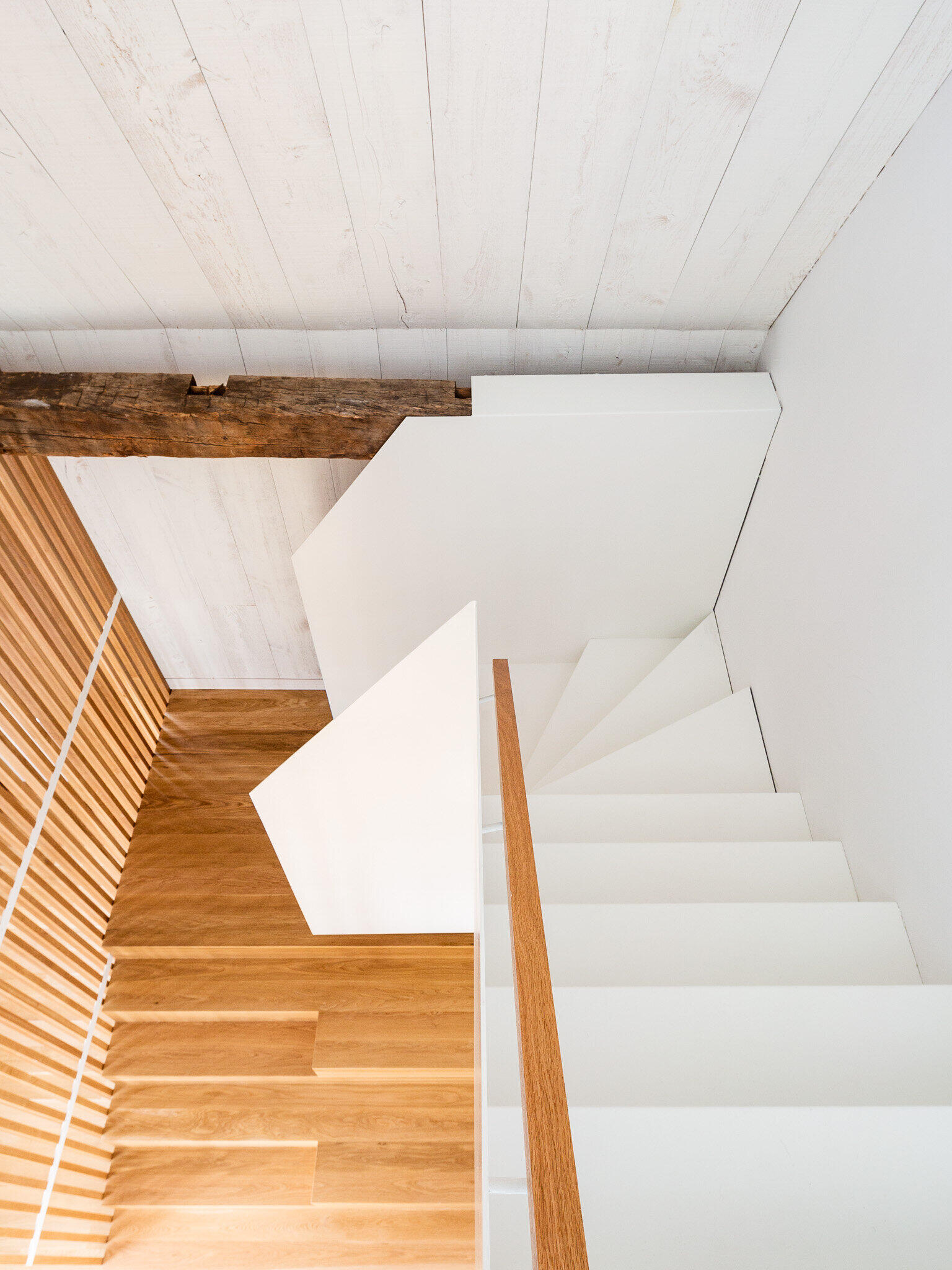 A light wood and white staircase connects the levels of the barn without disrupting sightlines or natural light.