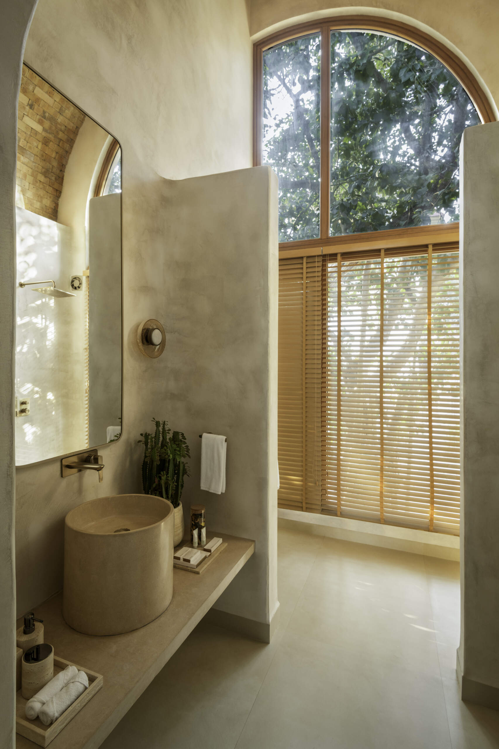 Seamless concrete curves, lime plaster walls and in-situ terrazzo basins shape cocoon-like bathrooms designed around natural light and tactile finishes.