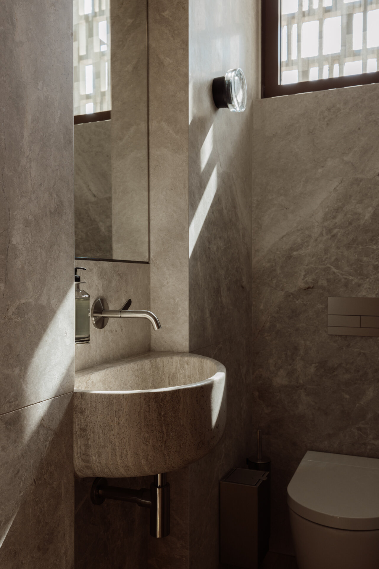 Tactile marble and ceramic bathrooms that continue a biophilic design approach focused on calm and connection to nature.