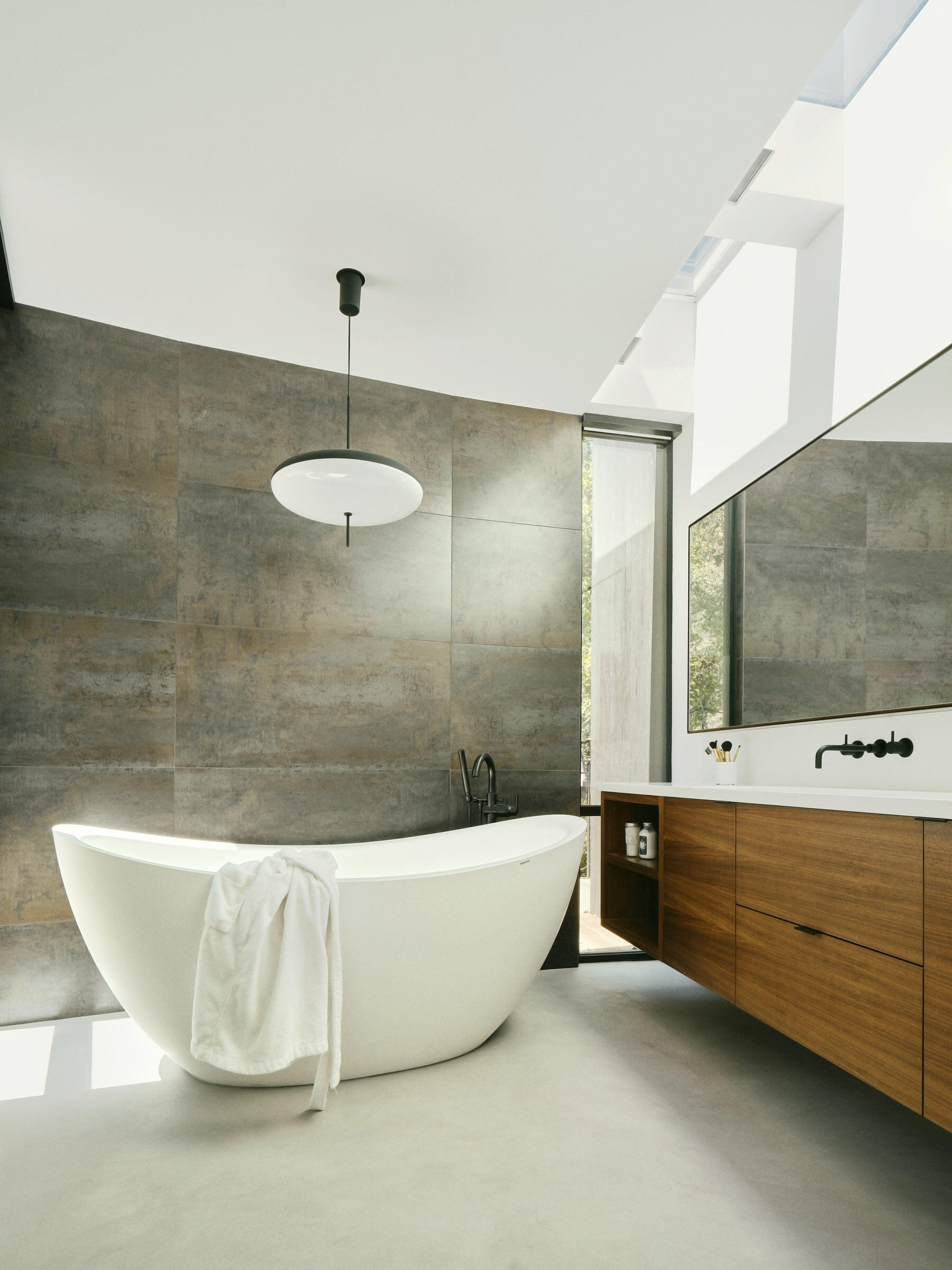 Bathrooms use the same restrained palette and curved forms, keeping attention on light, material continuity, and the surrounding landscape.