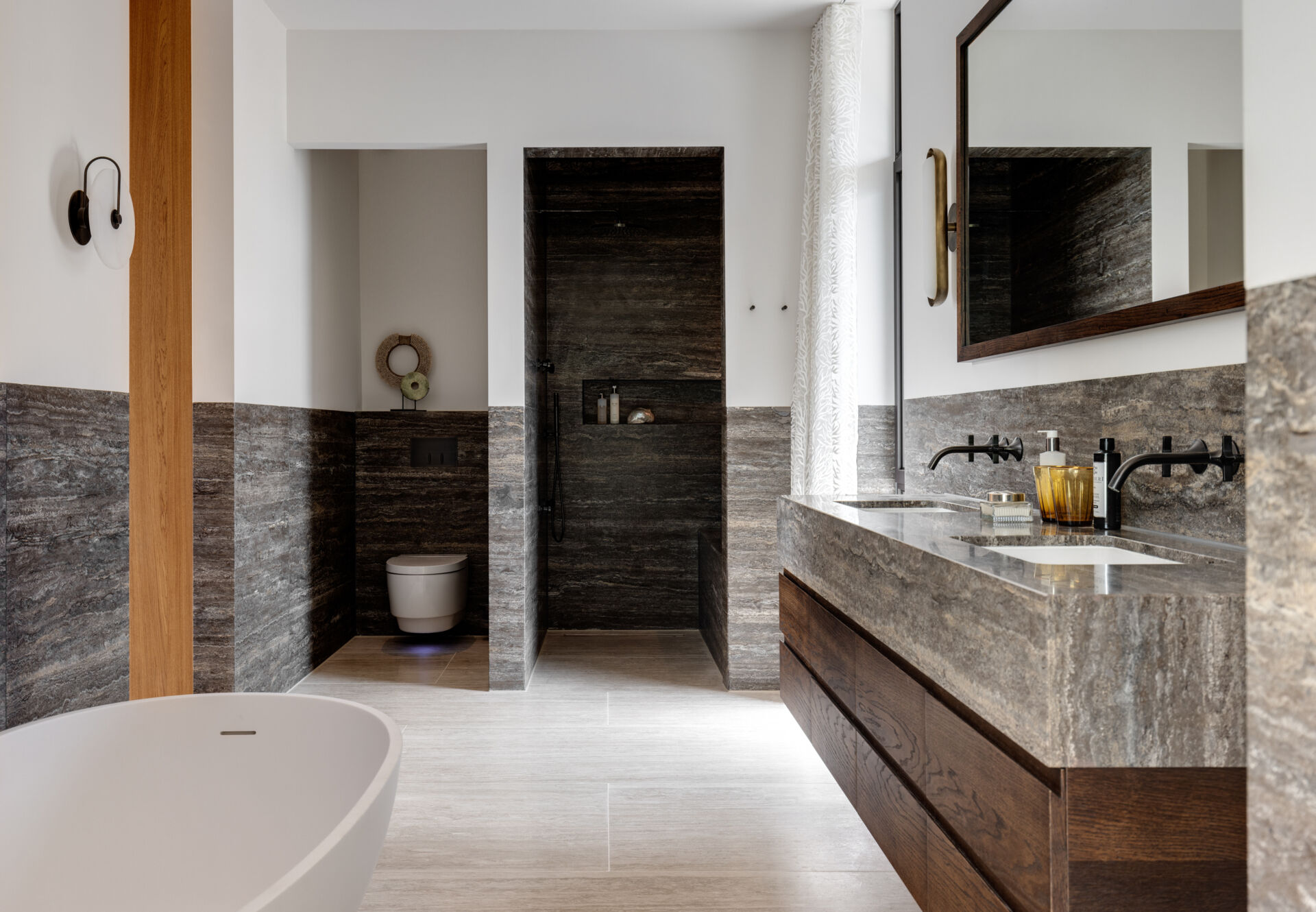 In this mid-century modern inspired bathroom, stone lines the bottom half of the walls and floor, and a window allows natural light to flow in.