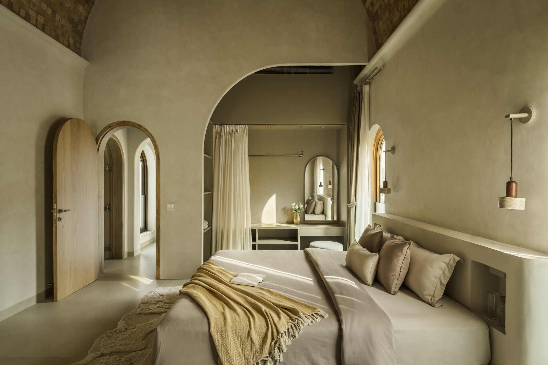 Each bedroom embraces artisan plasters, cane, wood and linen within a shared earthy palette, creating cool, monastic and cave-like atmospheres rooted in tactile comfort.