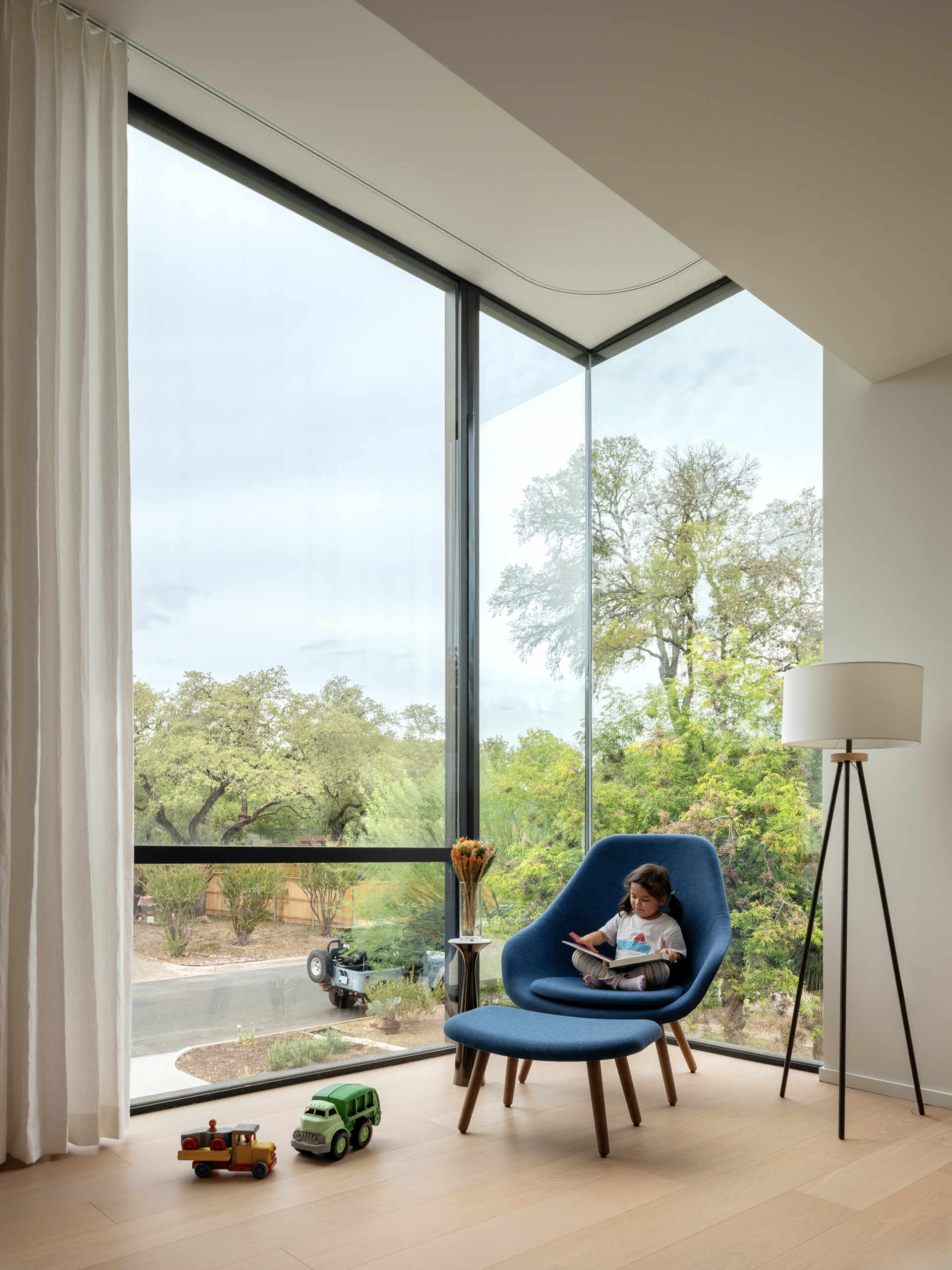 A playroom and media space positioned to take advantage of light and treetop views. A corner window opens the upper level to the outdoors while maintaining privacy below.