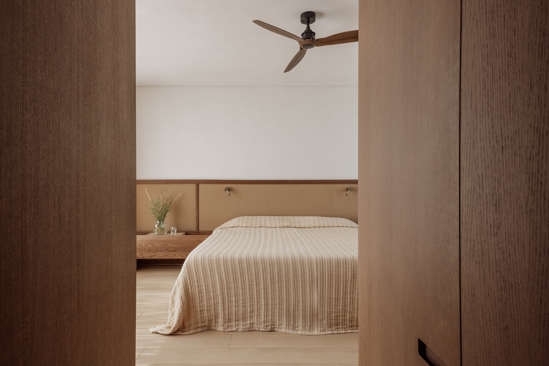 A modern bedroom has been finished with wood and earth tones.