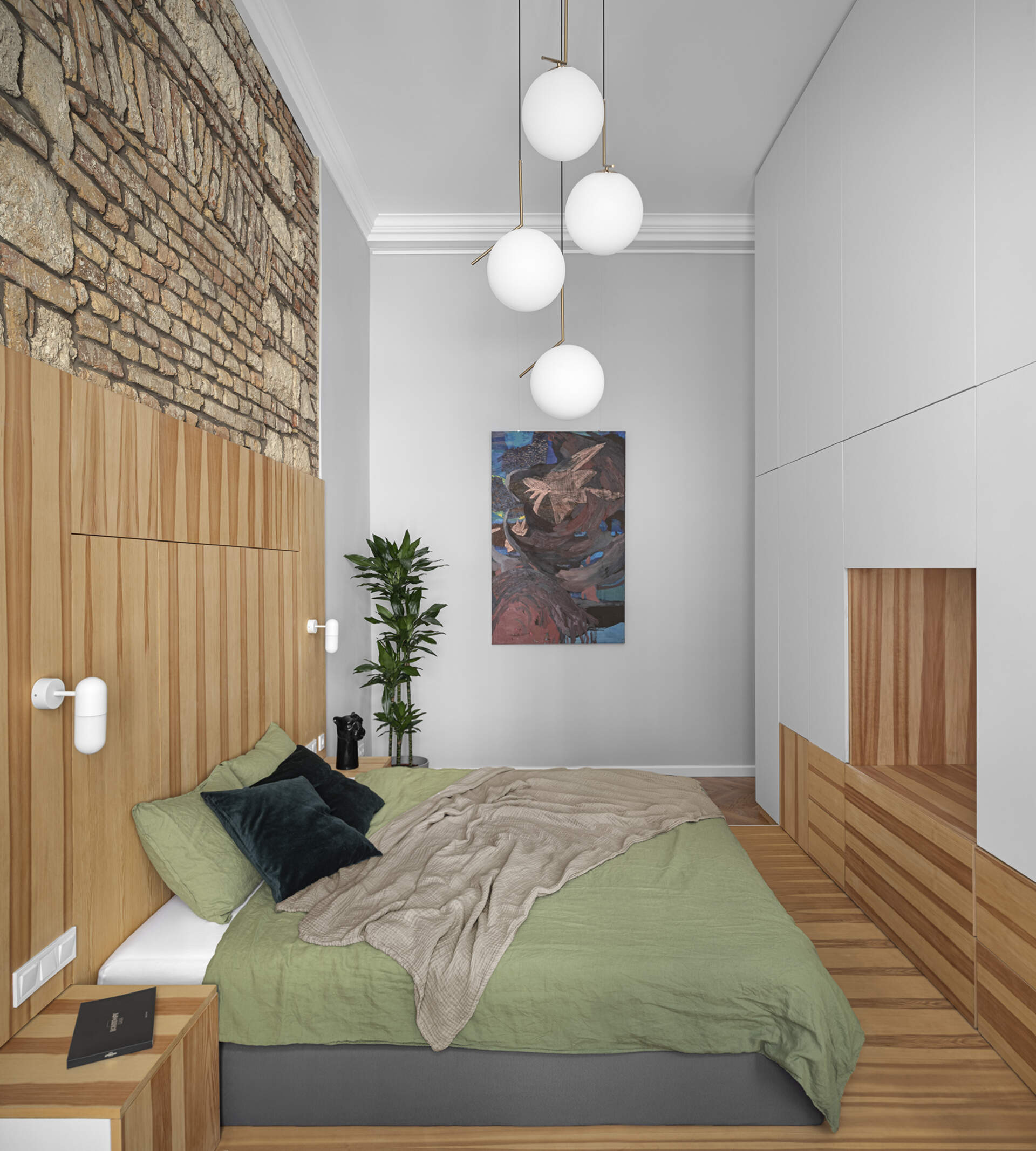 A high ceiling bedroom with exposed brick and stone, designed to shift easily from sleeping area to home office.