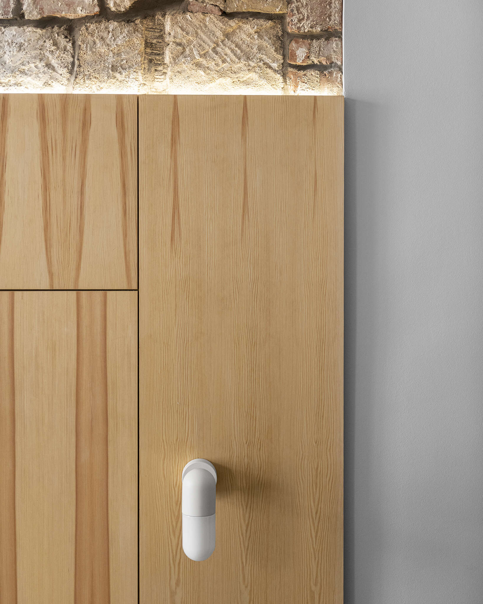 A high ceiling bedroom with exposed brick and stone, designed to shift easily from sleeping area to home office.