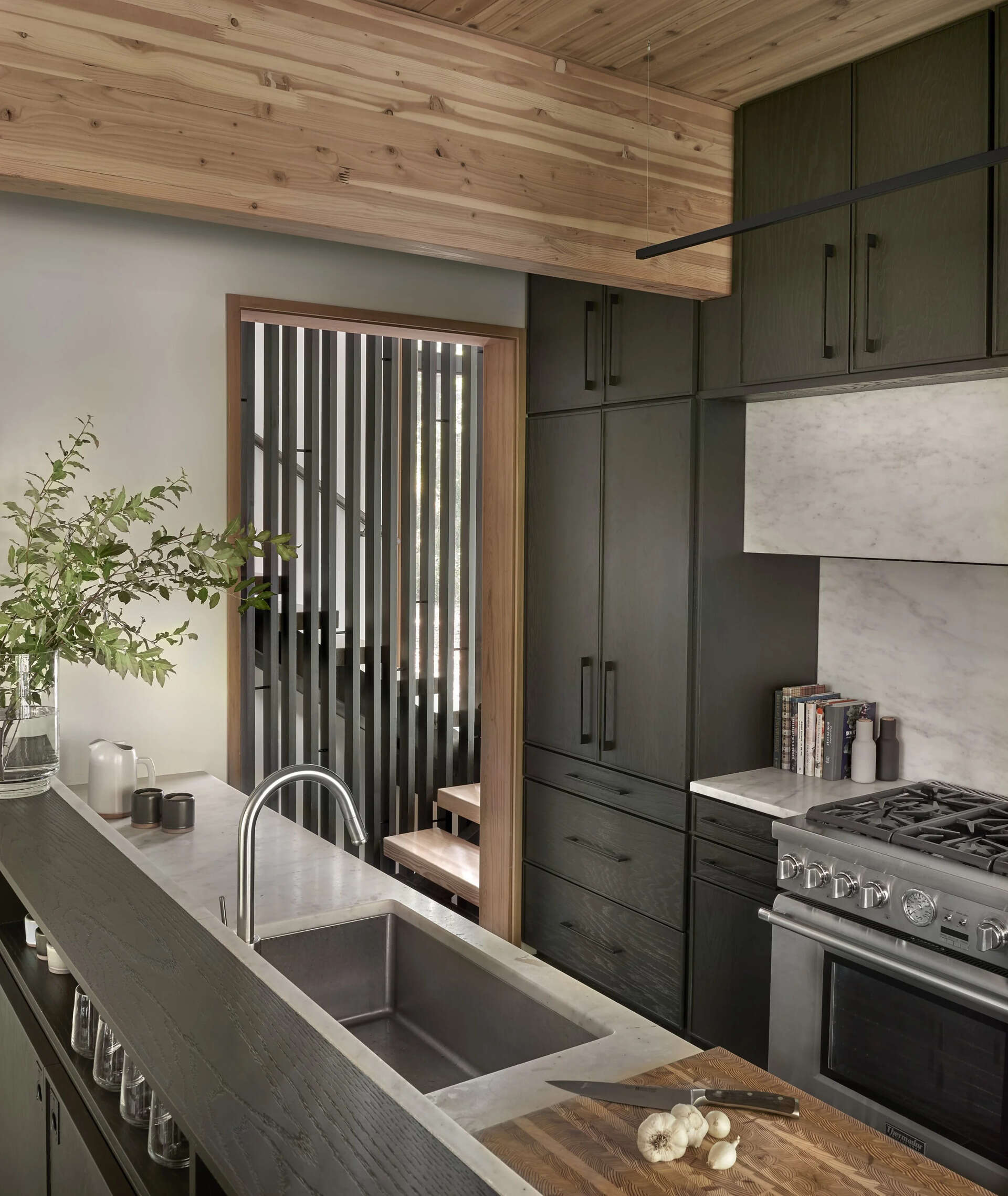 Dark stained oak cabinets and black slate floors define a terraced kitchen and dining space that follows the natural slope of the land.