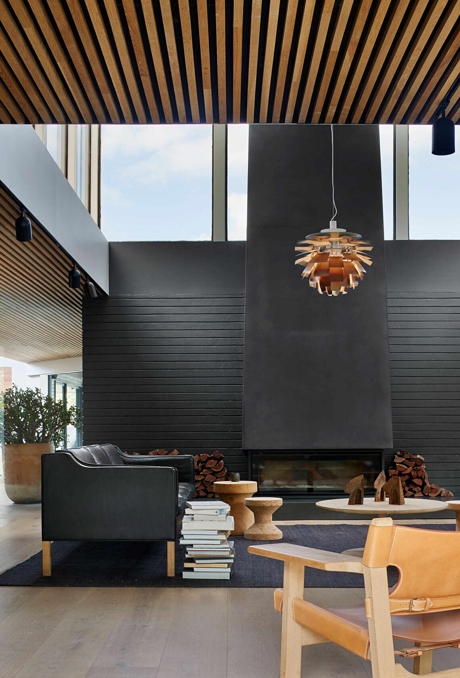 A black steel fireplace and a single pendant light anchor the living room, balancing openness with intimacy and focus.