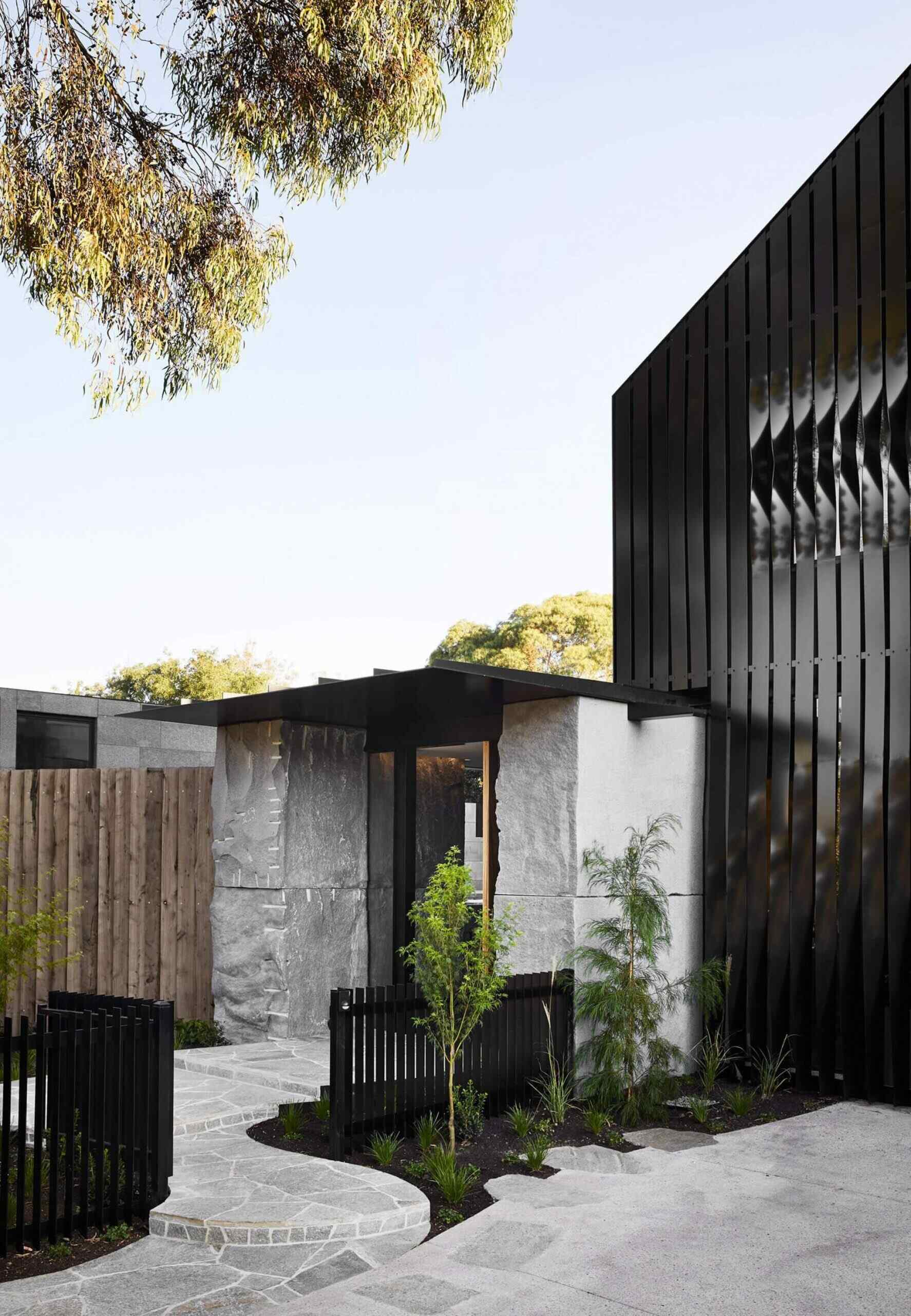 This Melbourne home in Northcote is built around 12 massive boulders, craned into place before construction even began. Black steel cladding and raw stone create a dramatic, quarry inspired facade that feels bold and sculptural.