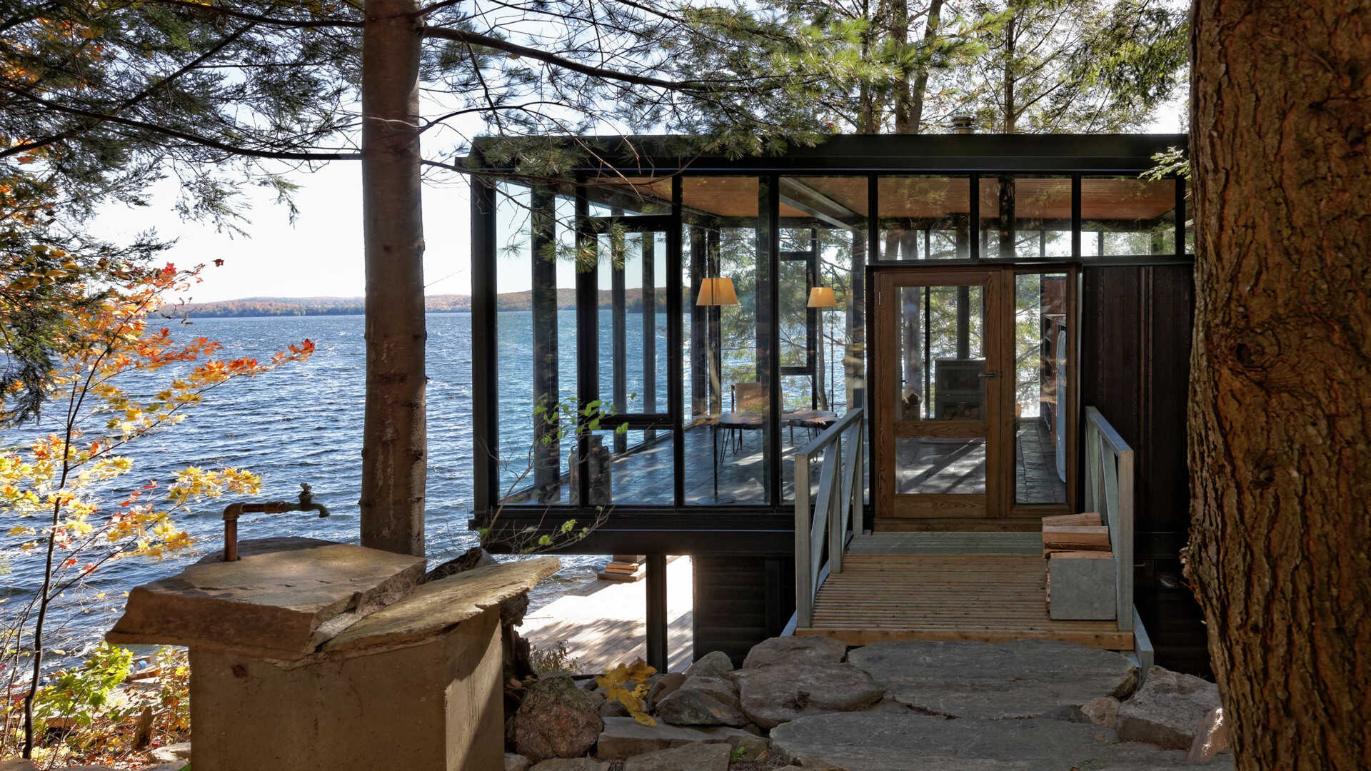 A small bridge spans the natural topography, creating a subtle and thoughtful approach to the elevated living space of this lakeside boathouse.