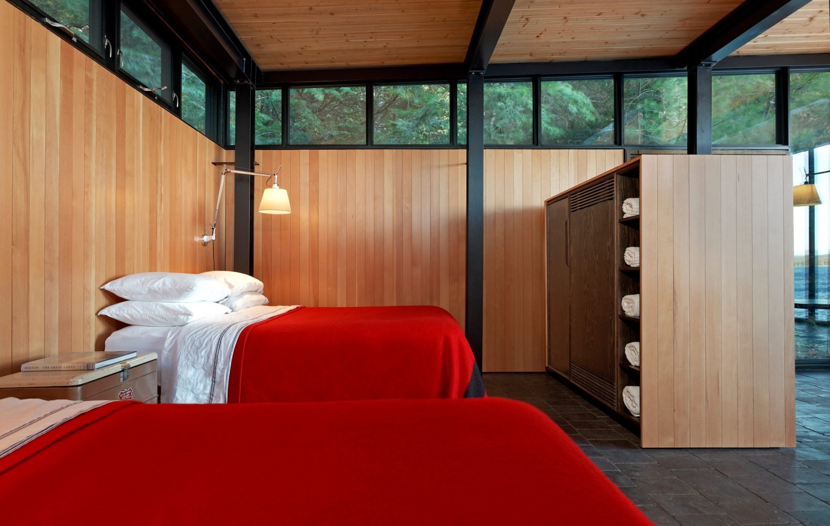 Shelving divides the sleeping area from the main living space, with wood lined walls and clerestory windows providing light and privacy.