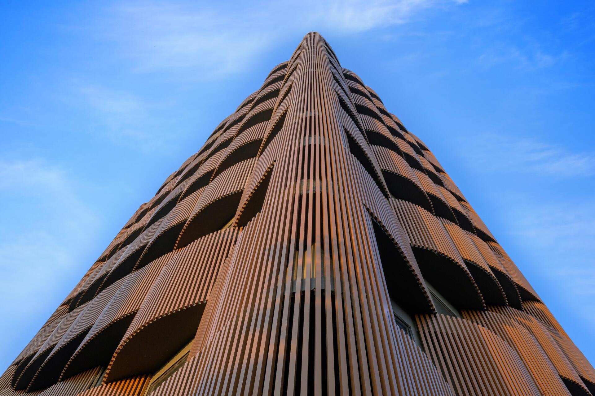This 14-level office in Nagpur replaces the typical glass facade with layered decks, aluminum louvers, and greenery designed for 48°C summers. A climate-smart approach to modern workplace design.