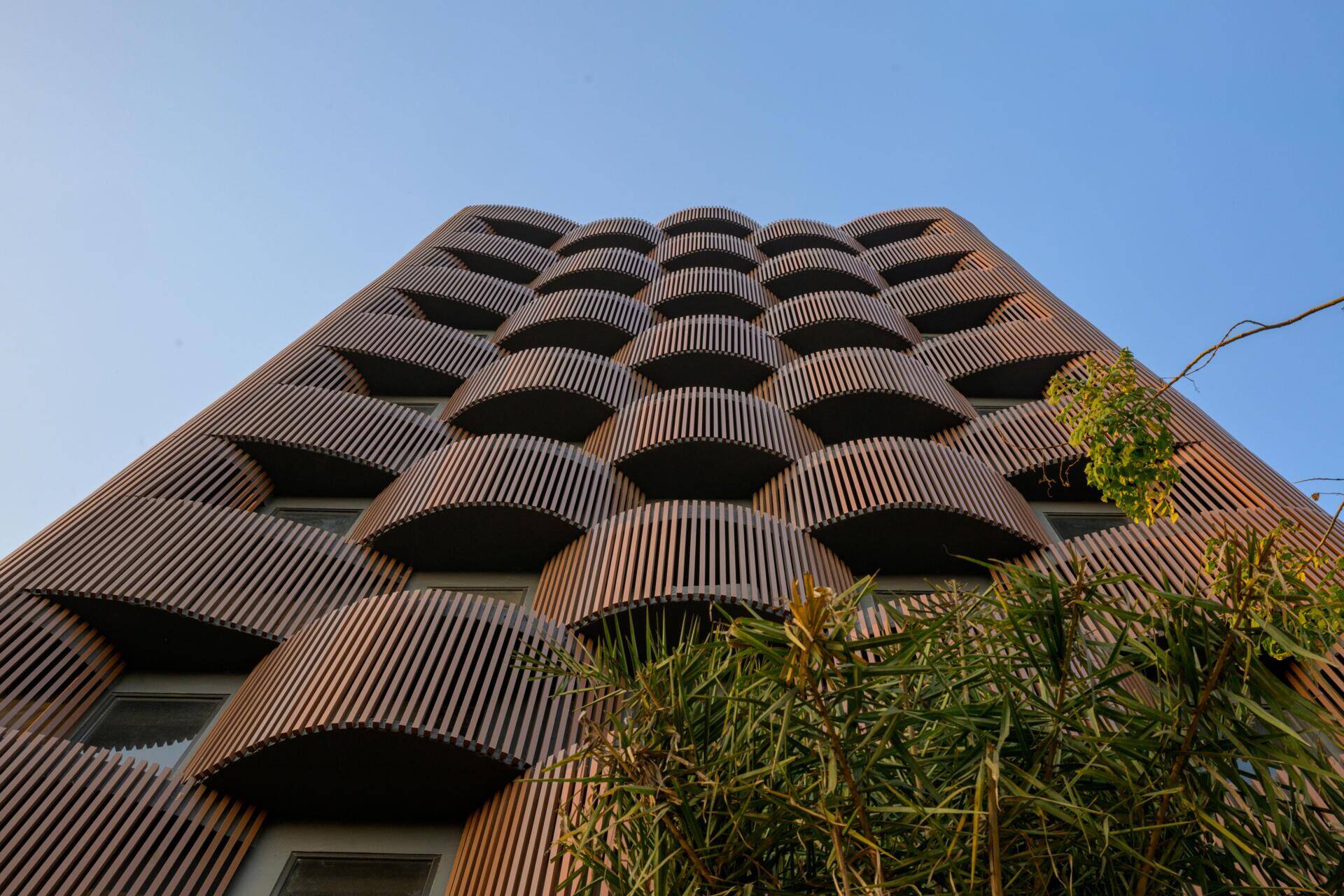 This 14-level office in Nagpur replaces the typical glass facade with layered decks, aluminum louvers, and greenery designed for 48°C summers. A climate-smart approach to modern workplace design.
