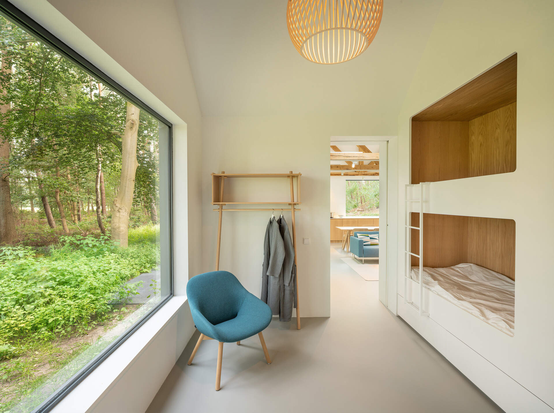 Located just off the social areas is the children’s bedroom, where built-in bunk beds lined with wood create snug sleeping nooks. Positioned in front of a large window, the beds overlook the woods, giving children a direct view of birds and deer from the comfort of their own corners.