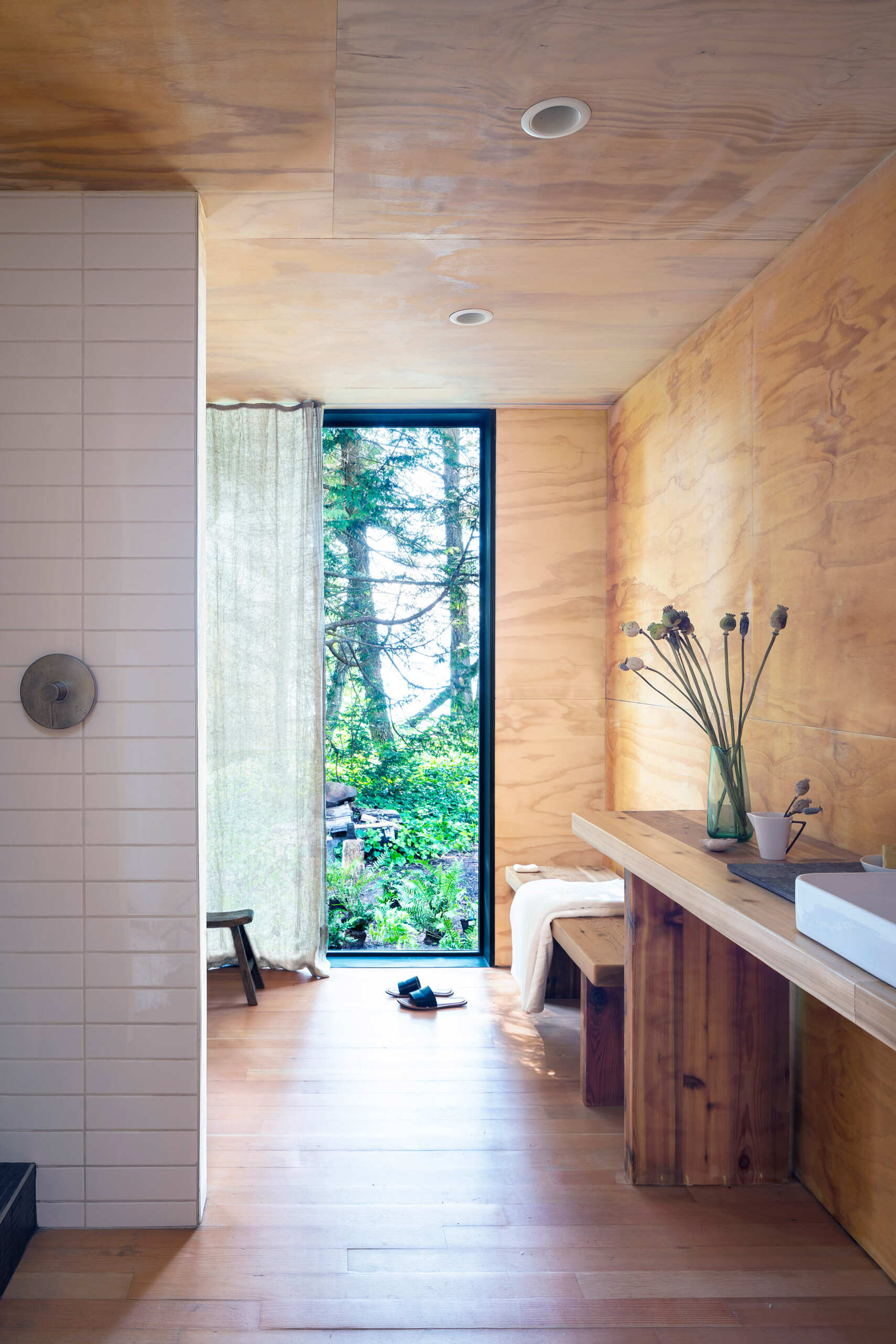 A reclaimed cast iron tub set against forest views creates the feeling of bathing outdoors while remaining sheltered inside.