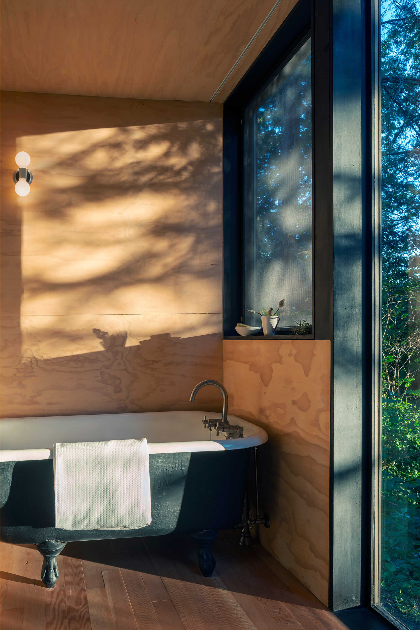 A reclaimed cast iron tub set against forest views creates the feeling of bathing outdoors while remaining sheltered inside.