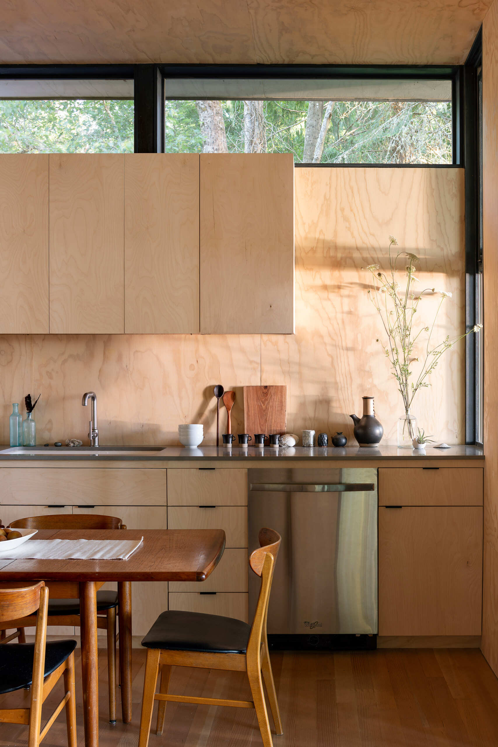 A pass through kitchen window extends the countertop outdoors, connecting cooking, dining, and social life with the surrounding landscape.